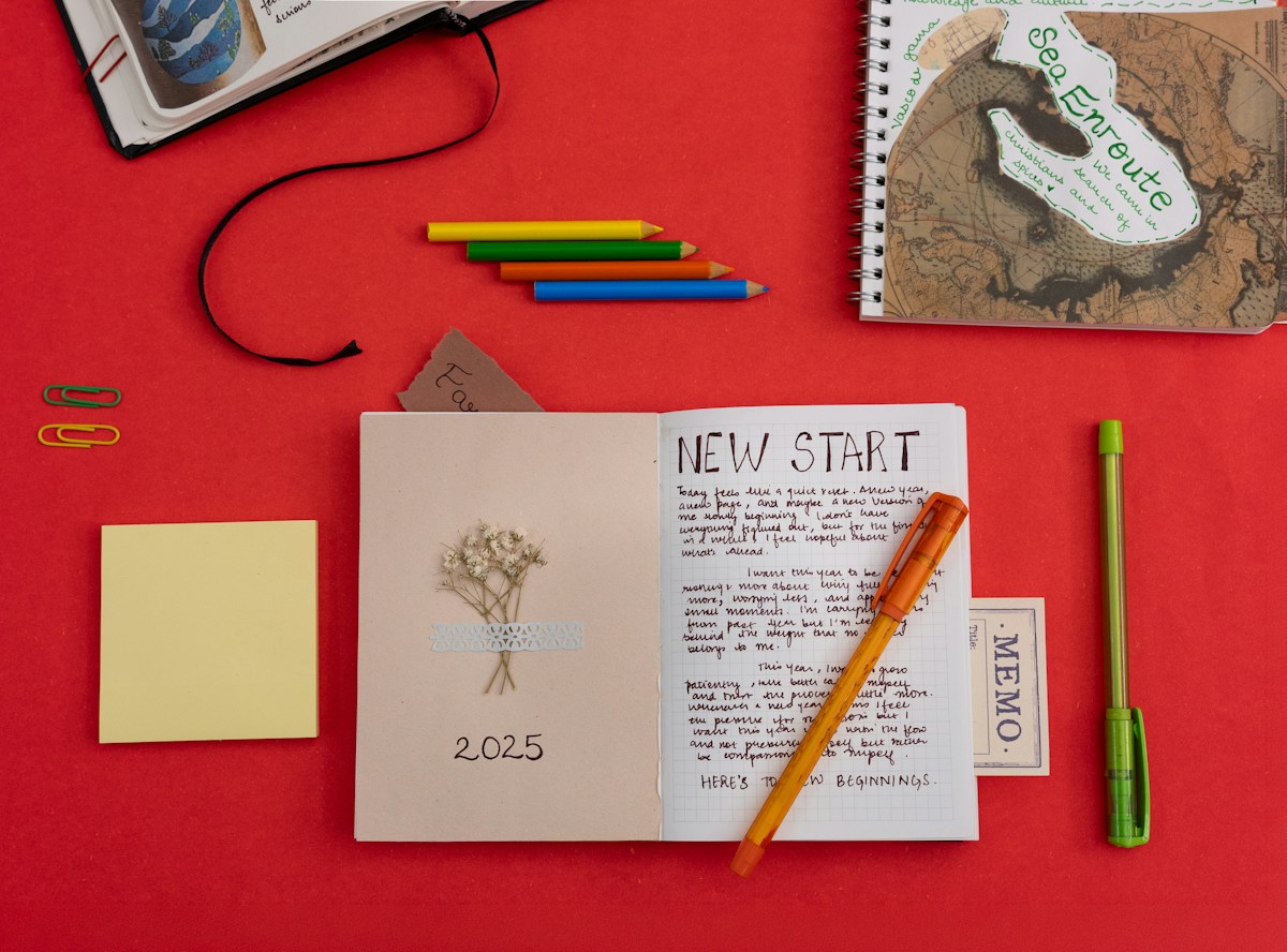 Notebook labeled 'new start' with colorful pens, pencils, and sticky notes, ideal for spring carnival planning notes.
