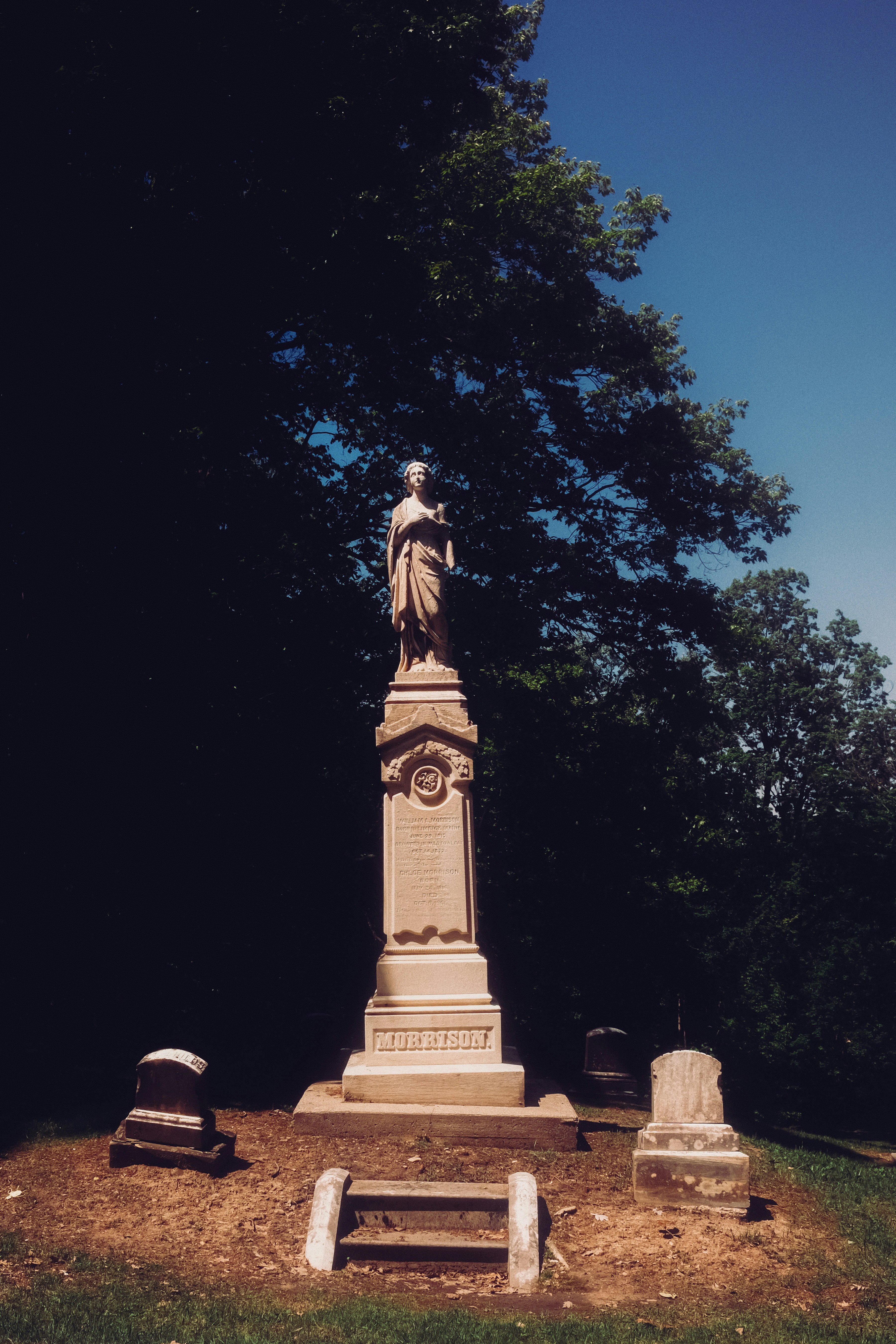 Ein hohes Steinmonument mit einer Statue auf einem Friedhof.