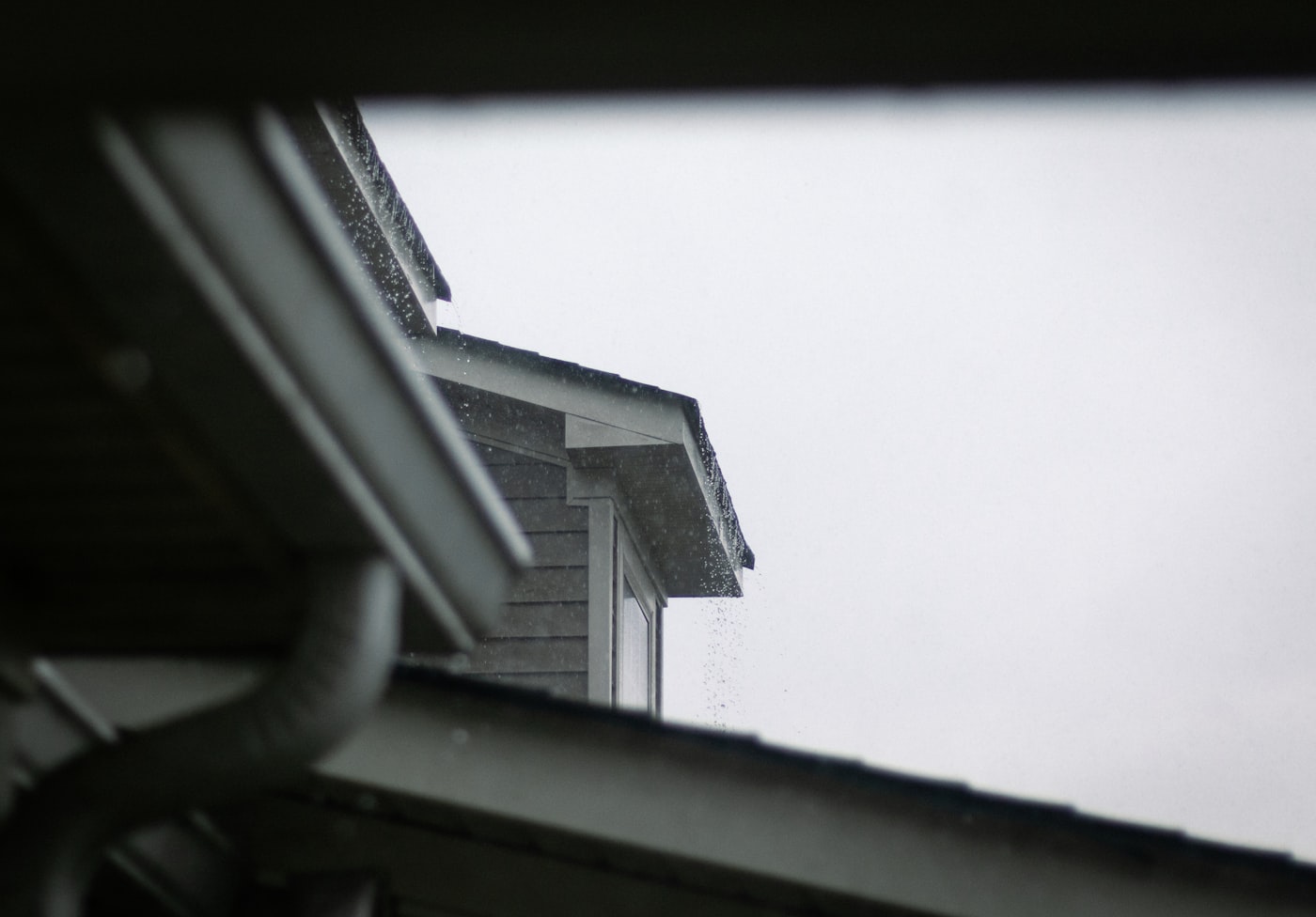 Roofline with a gutter system against a grey sky