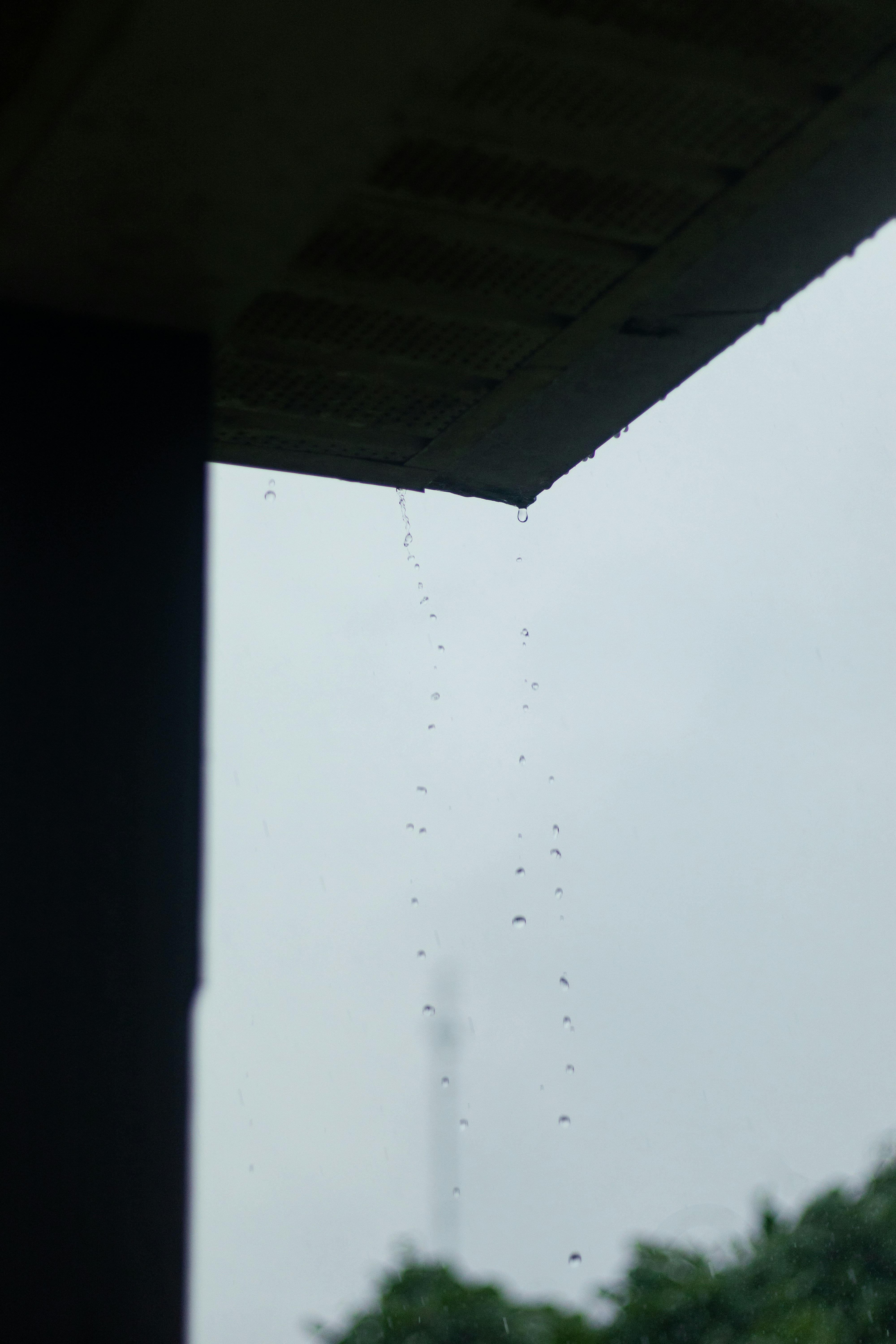 Tetesan hujan jatuh dari atap yang menggantung di langit kelabu.