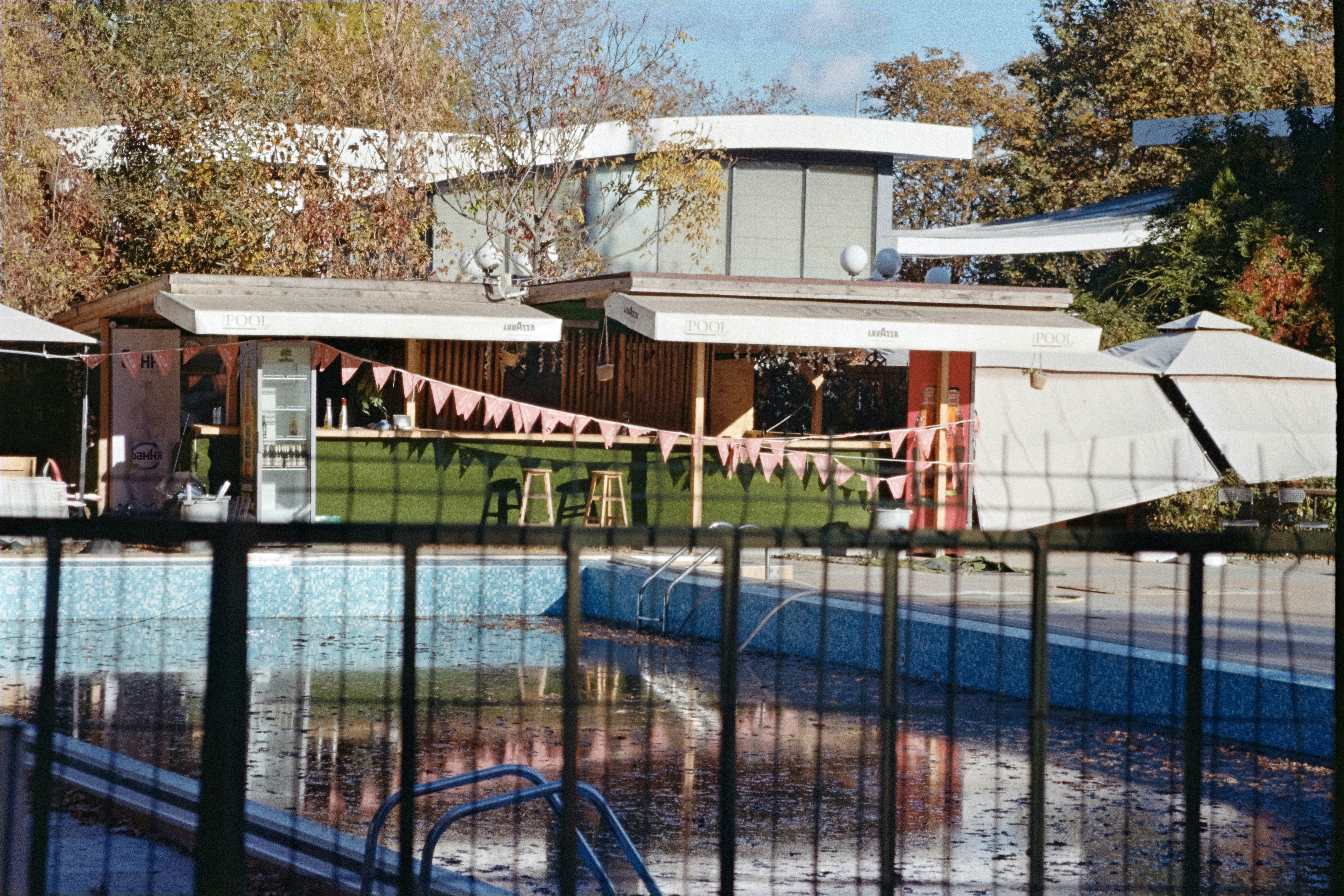 Empty swimming pool behind a fence with buildings in background