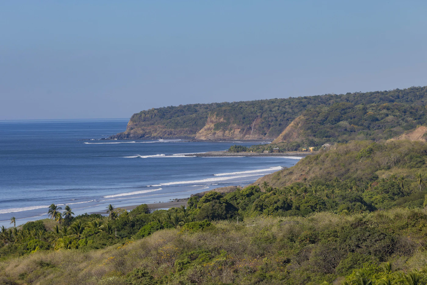 Wild beach and green cliffs at Playa Las Flores, El Salvador