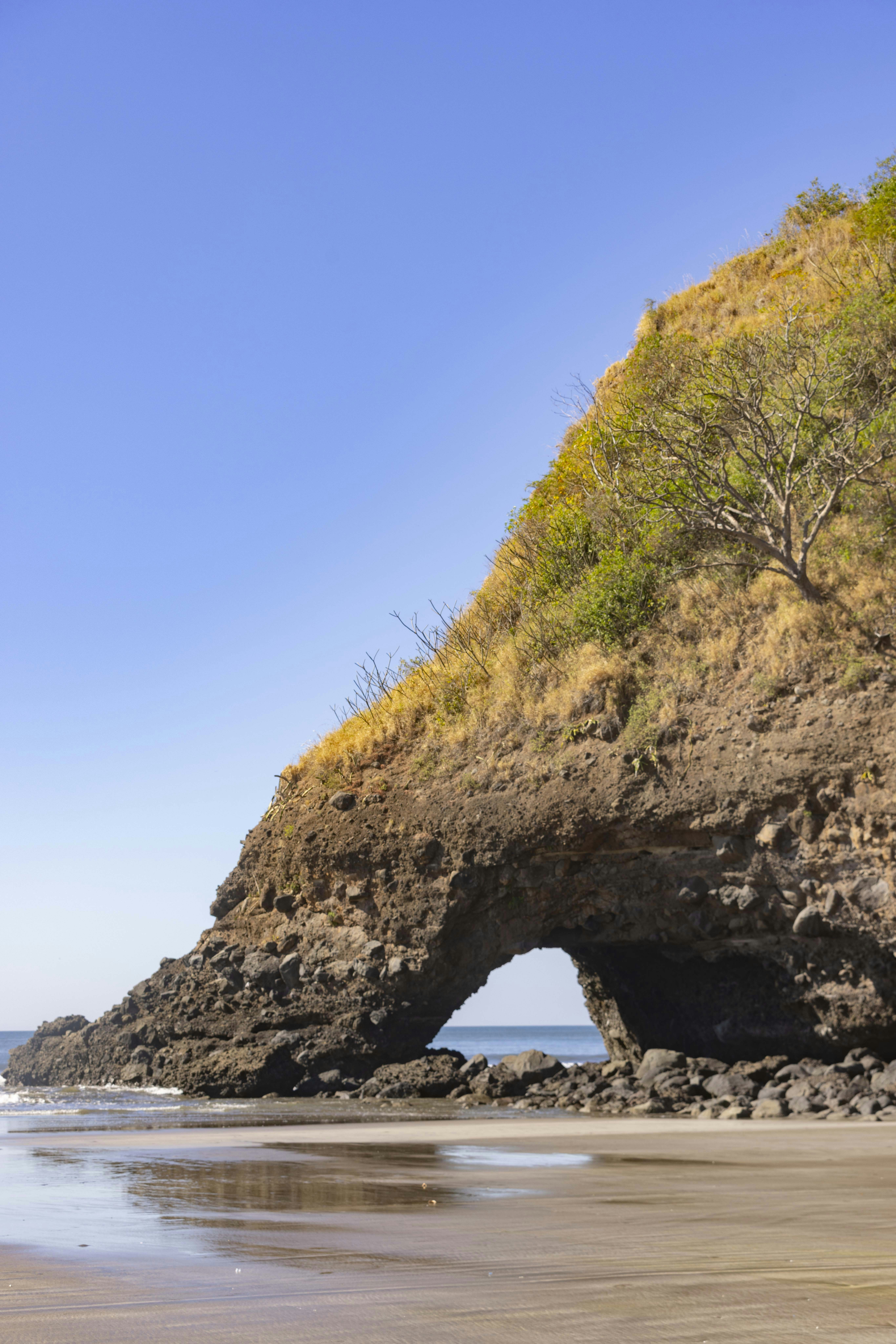 Arco rochoso natural em uma praia de areia sob céu azul