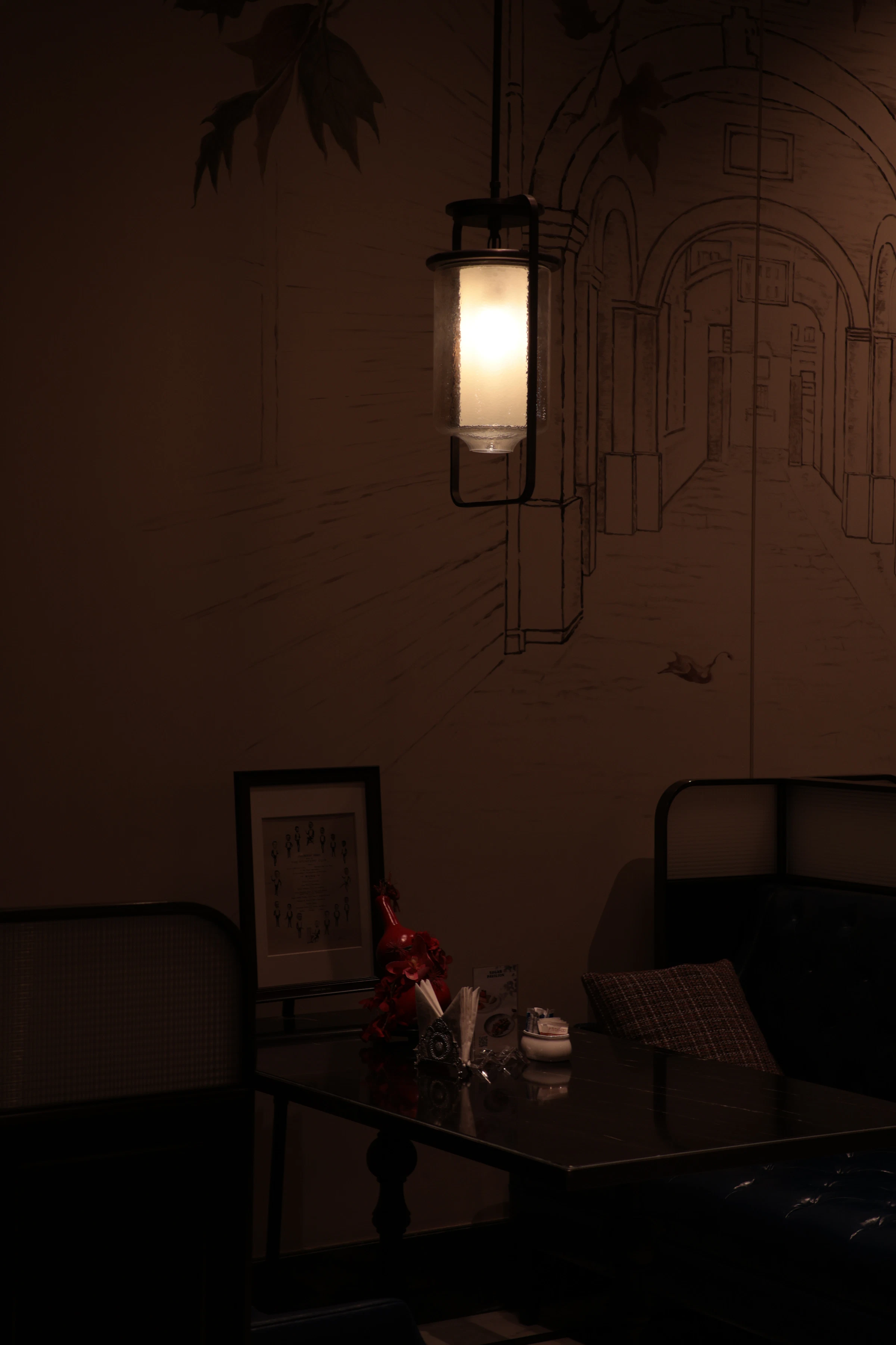 A dark dining table under the warm glow of a hanging pendant lamp