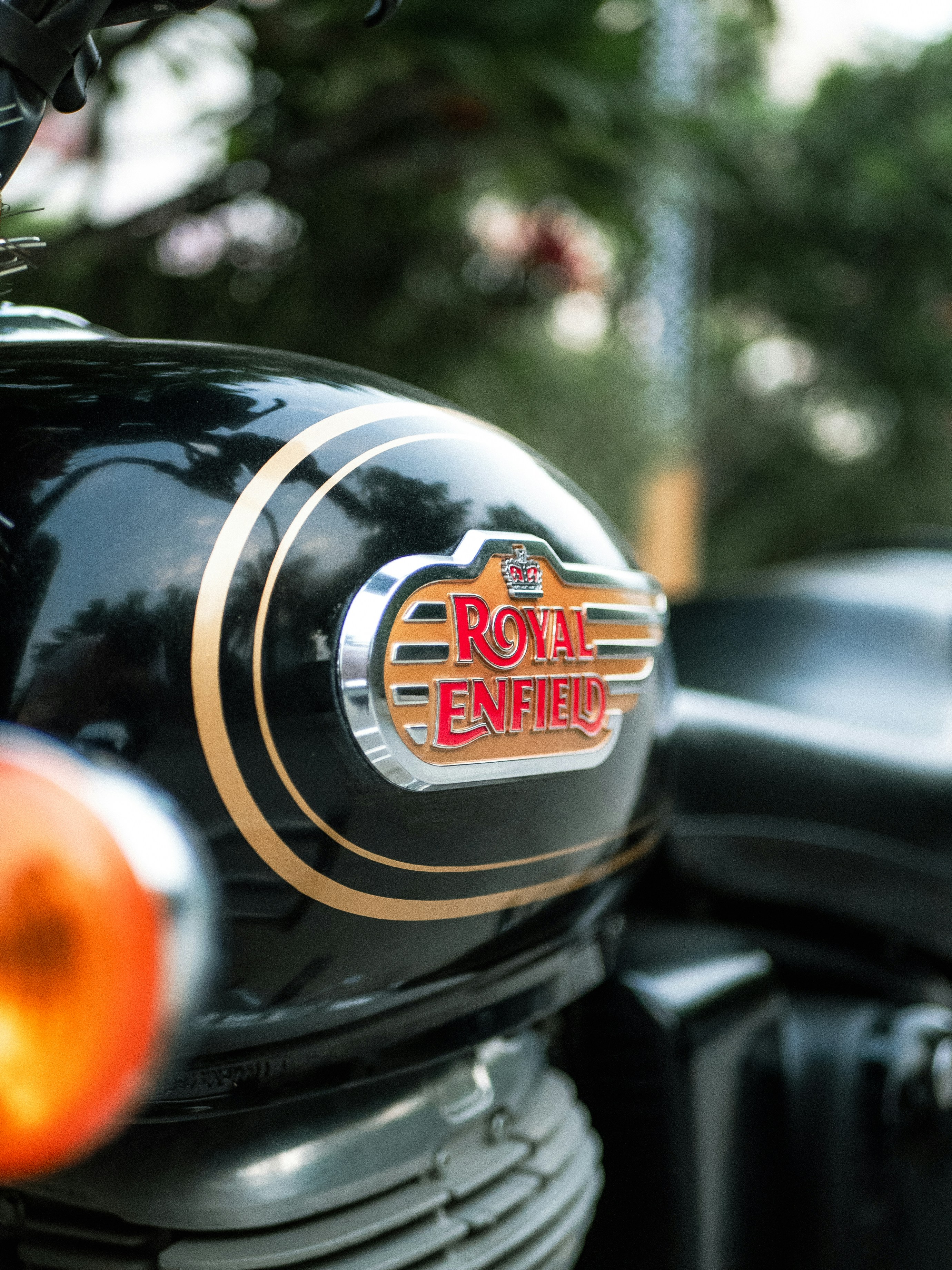 Close-up of a black royal enfield motorcycle tank emblem.