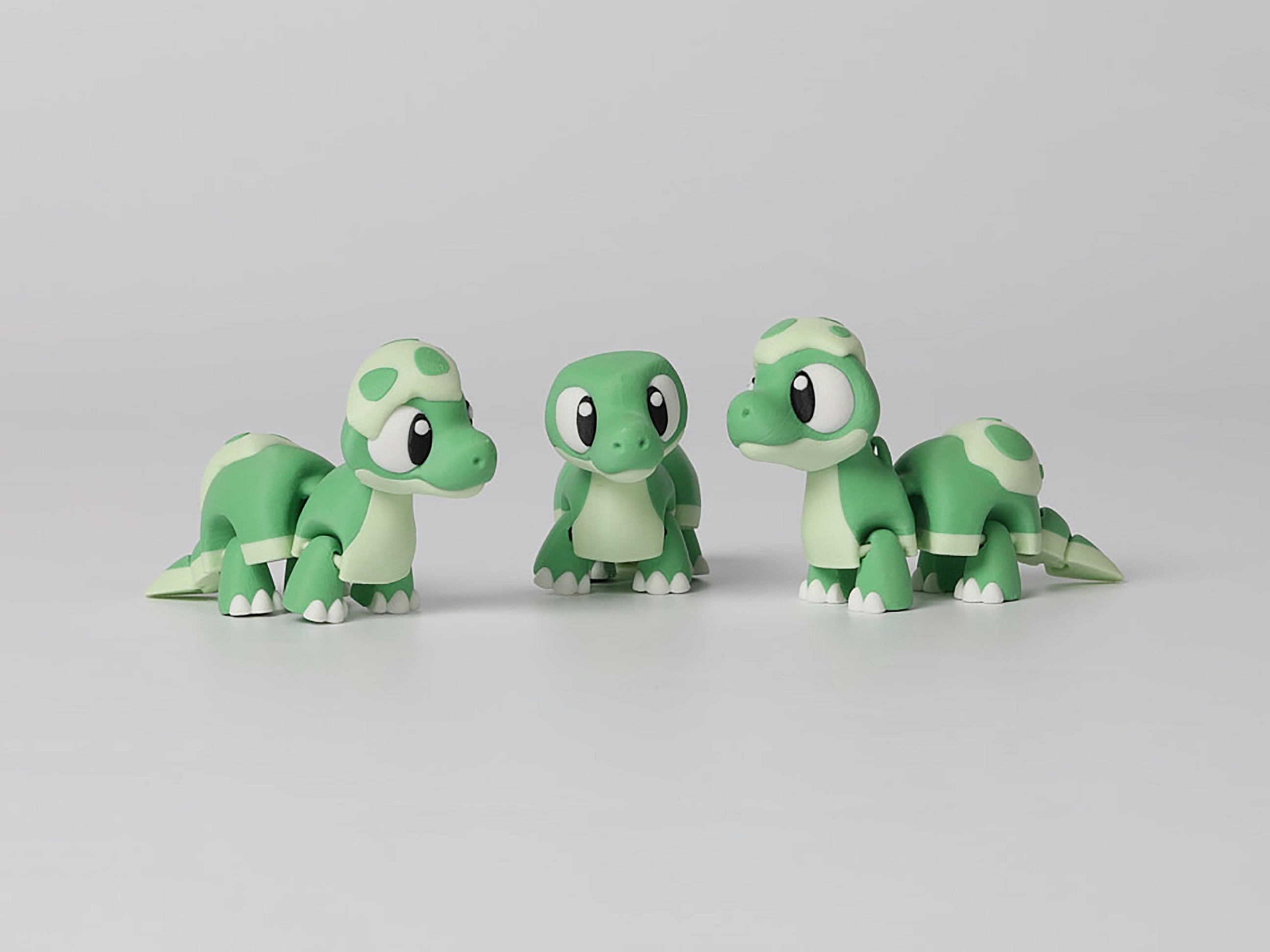 Drei grüne, schildkrötenähnliche Figuren auf weißem Hintergrund.