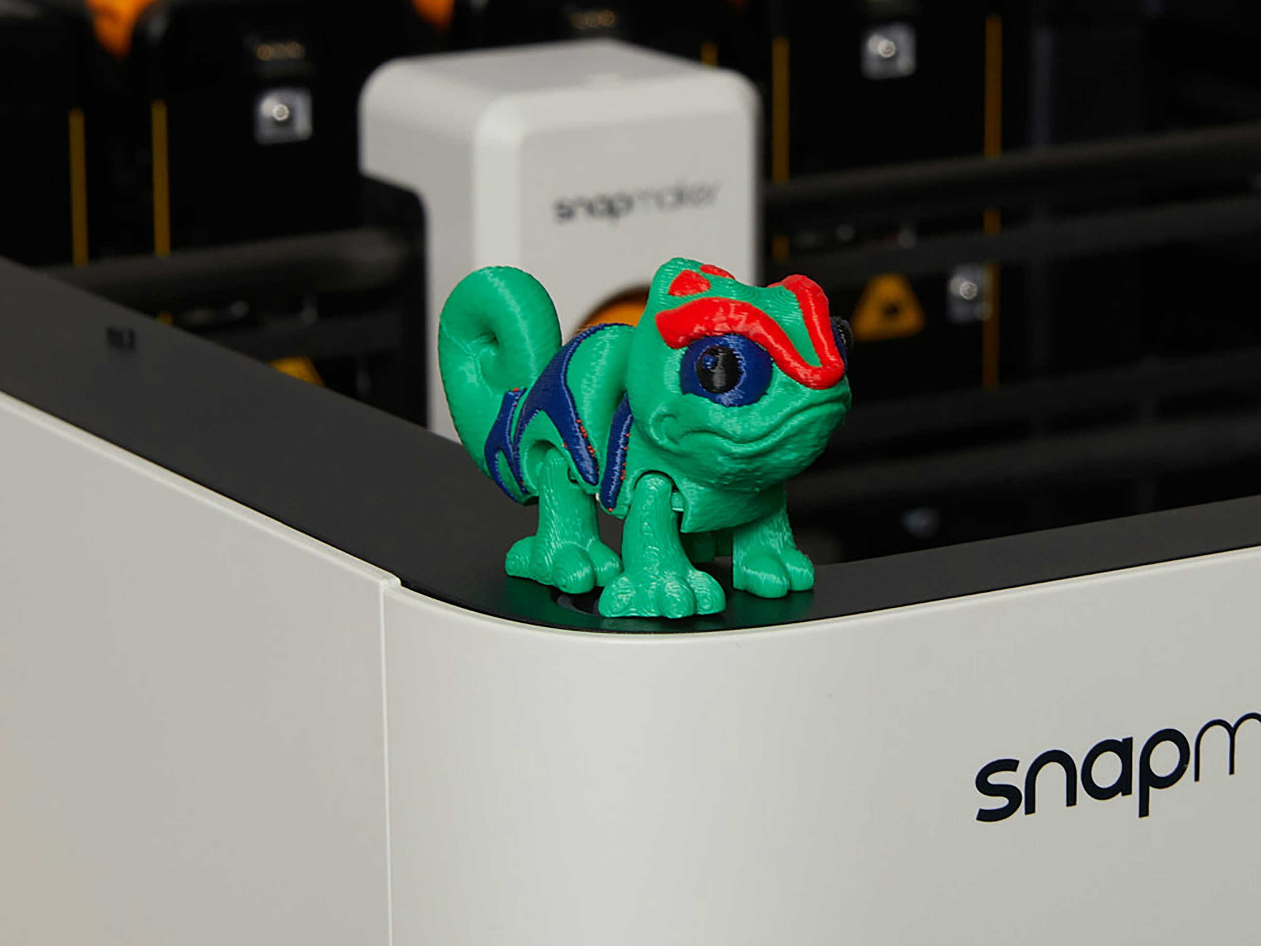 Ein buntes Chamäleon-Spielzeug steht auf einer Snapmaker-Maschine.