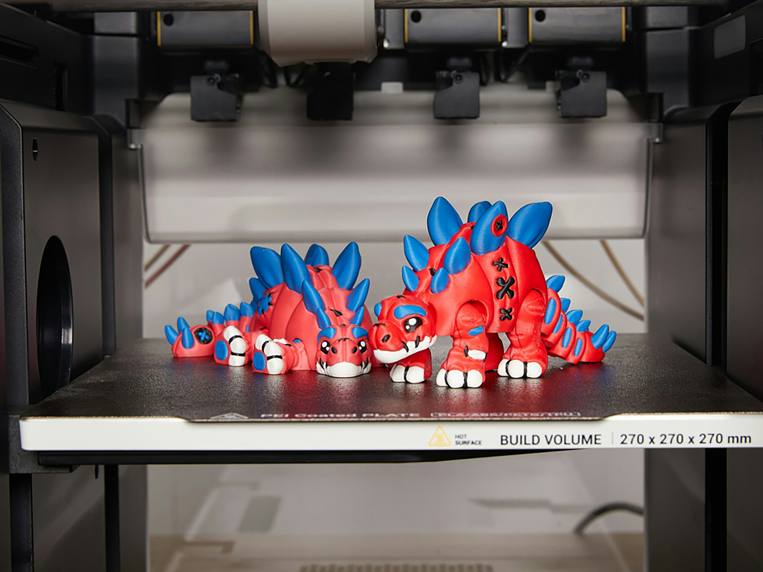 Zwei rot-blaue 3D-gedruckte Dinosaurierfiguren.