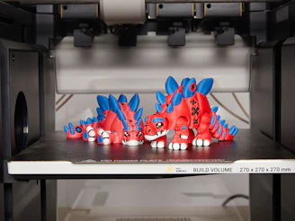Two red and blue 3D printed dinosaur figures.