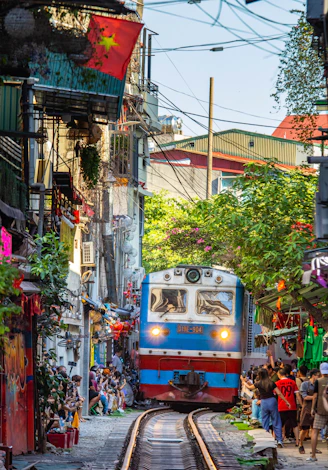 Train approaches narrow street lined with buildings and people