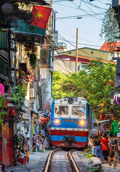Train approaches narrow street lined with buildings and people