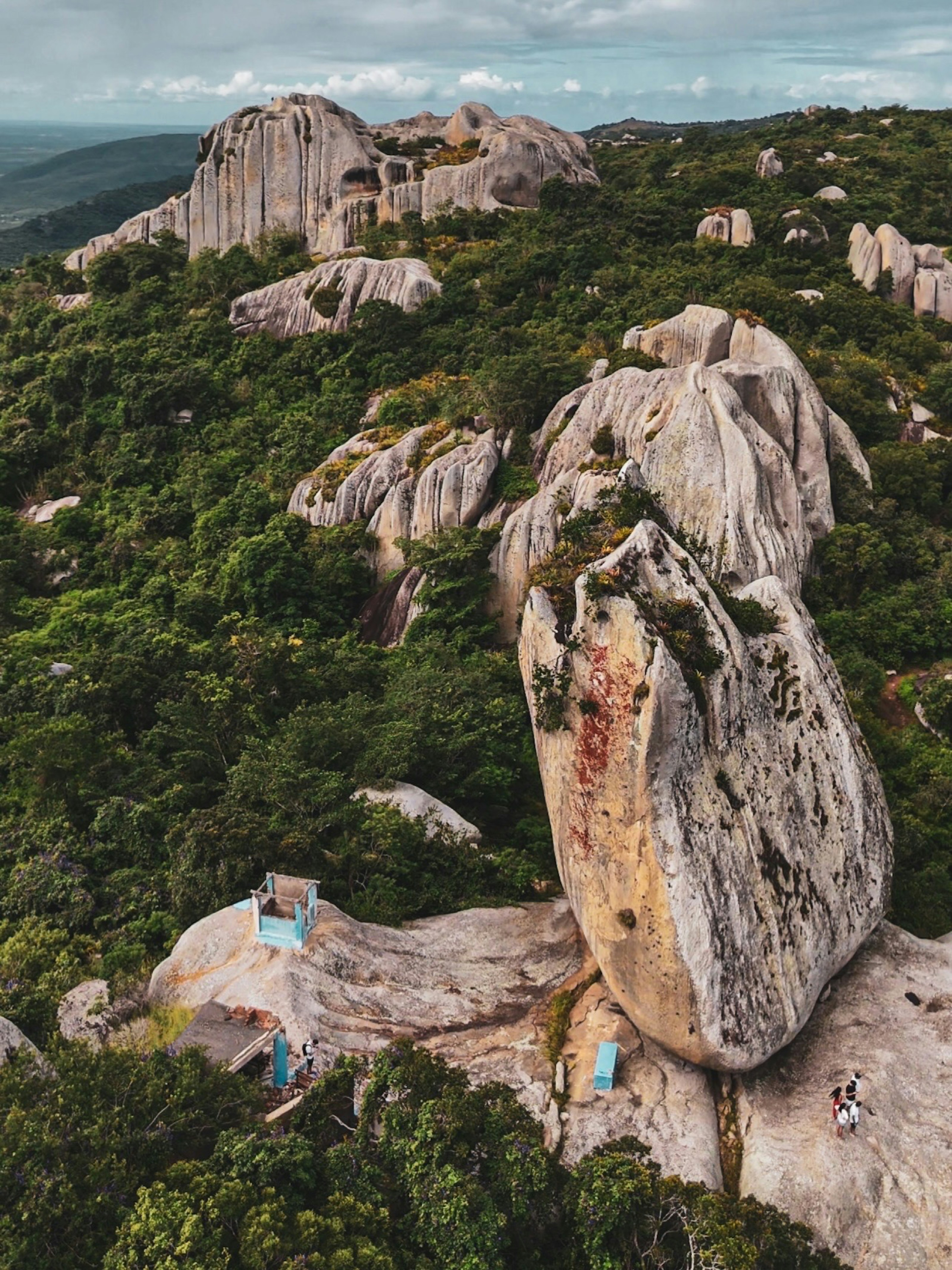 Large rock formations and green trees under a cloudy sky.