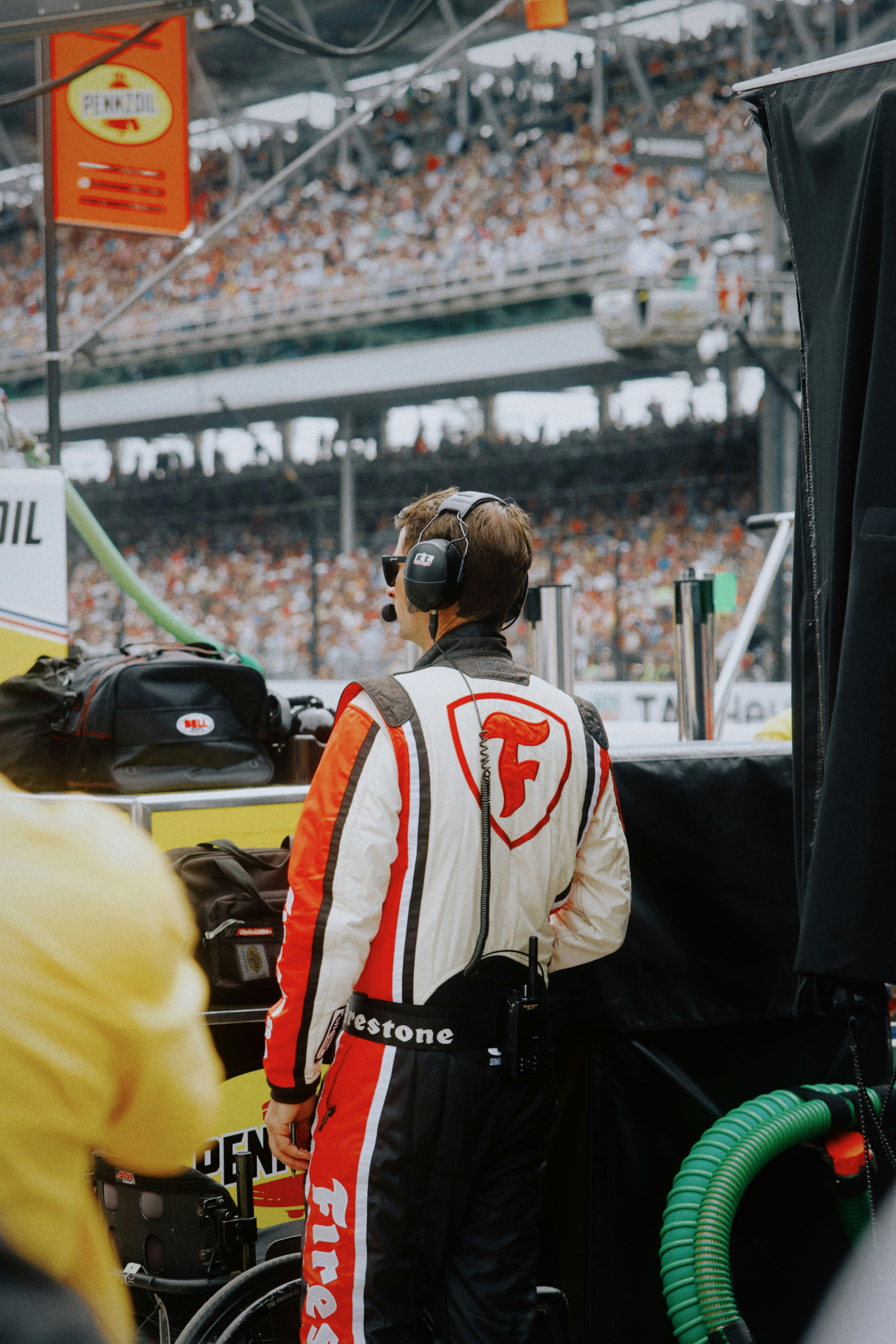 Pit crew member with headset observing the race track crowd.