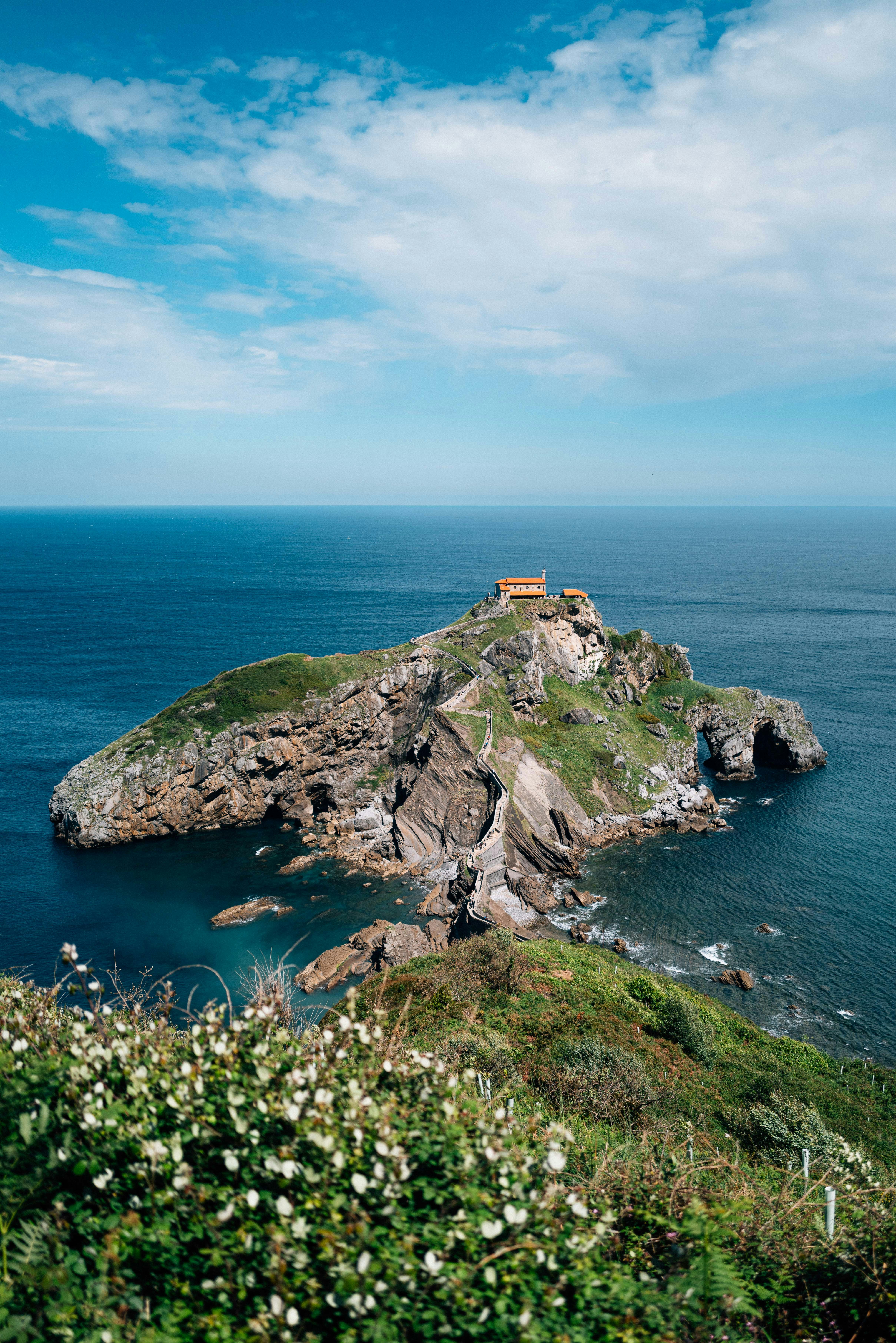 Rocky island with a building surrounded by blue ocean.
