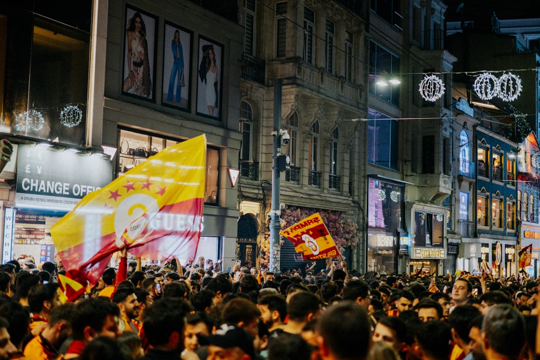 Large crowd celebrating with red and yellow flags at night.