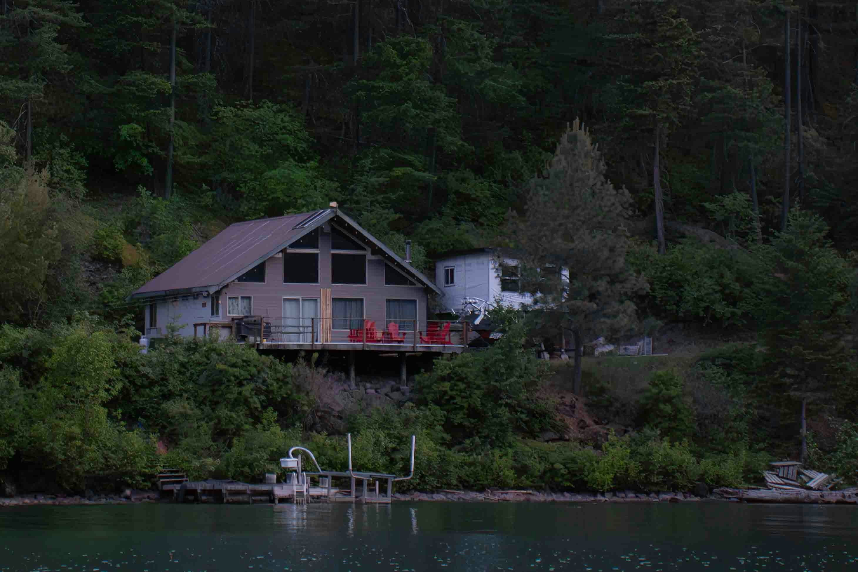 Lakeside house with a dock nestled in a wooded hillside.