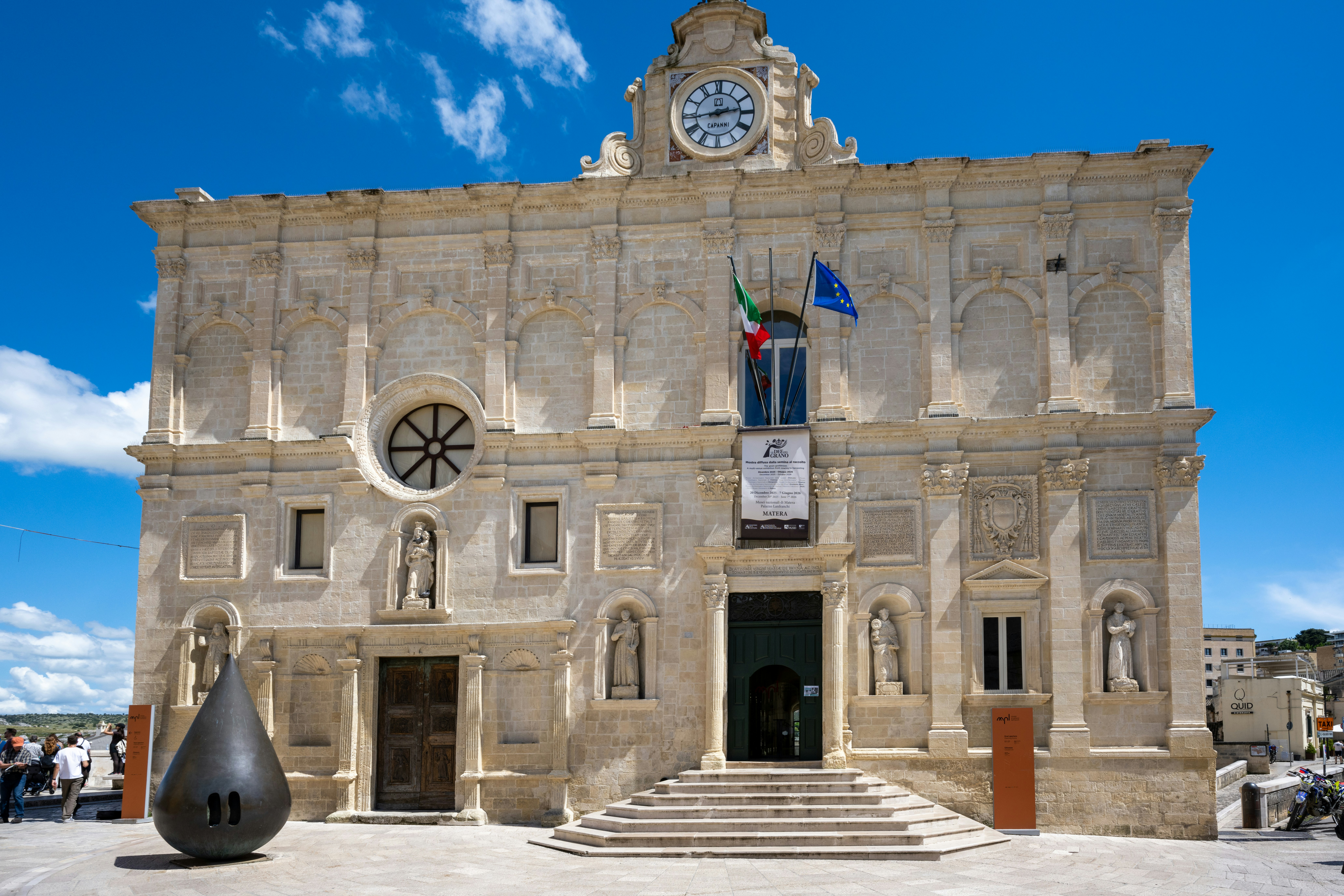 Historic stone building with clock and dark modern sculpture - Free ...