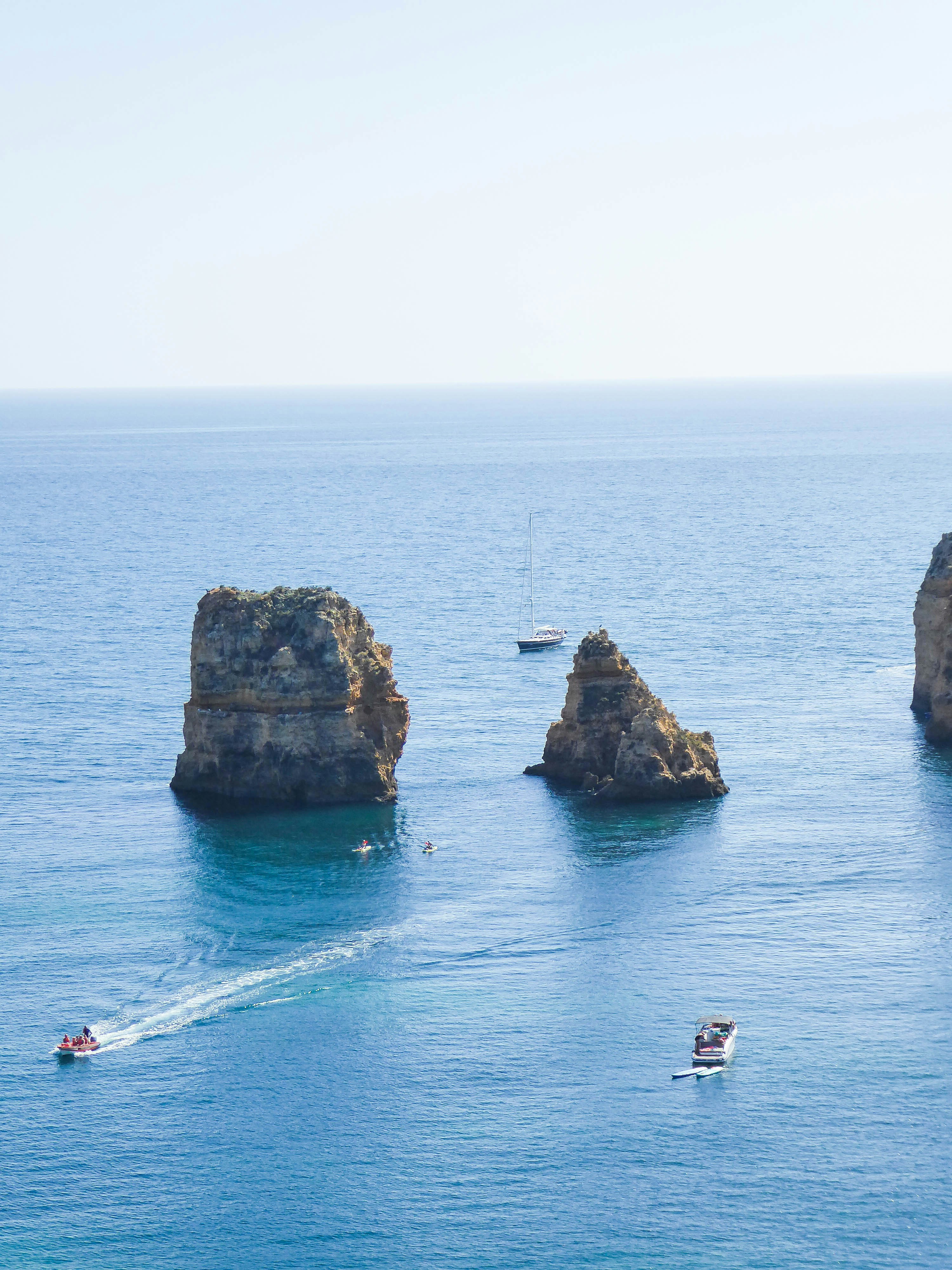 Les bateaux naviguent dans un océan bleu calme autour de grandes formations rocheuses.