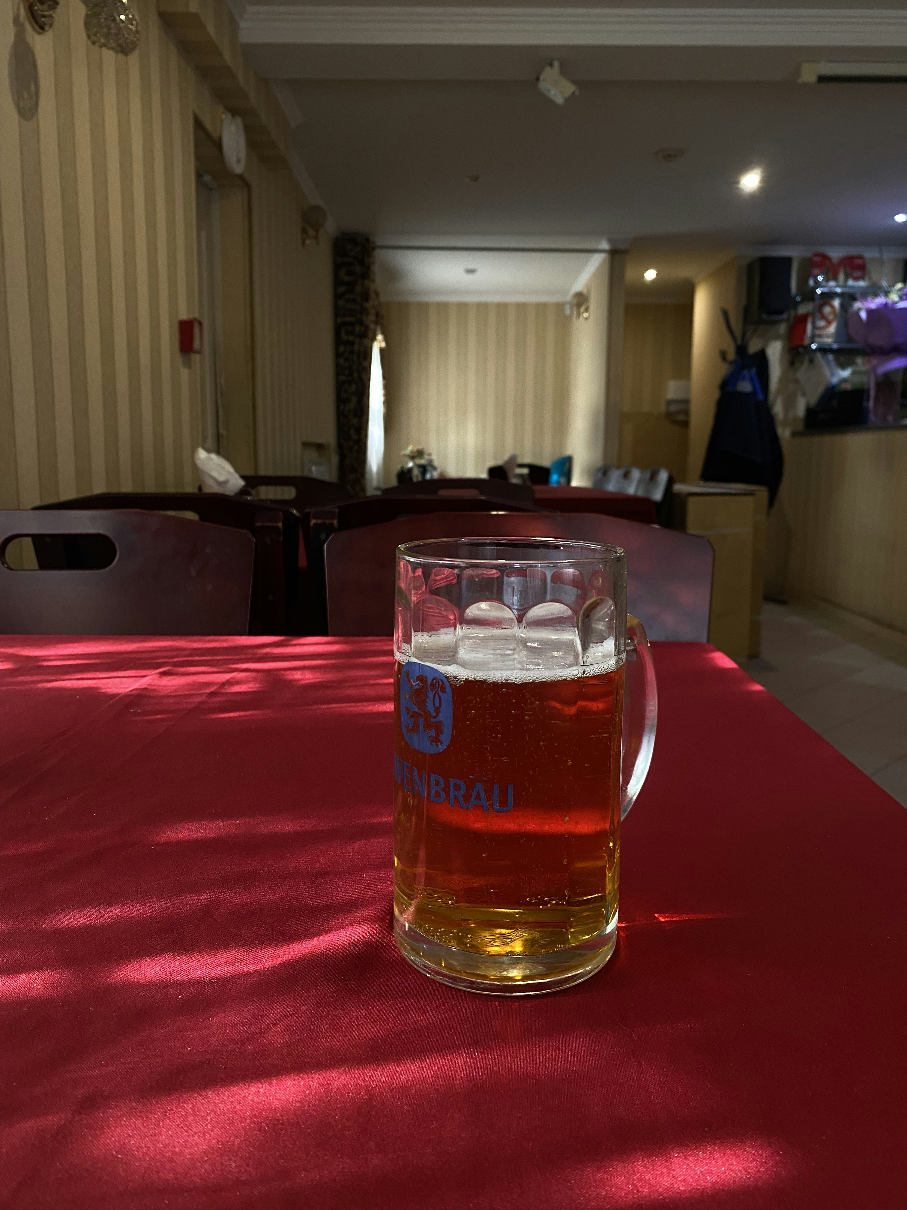 Beer mug on a red table with sunlight shadows.