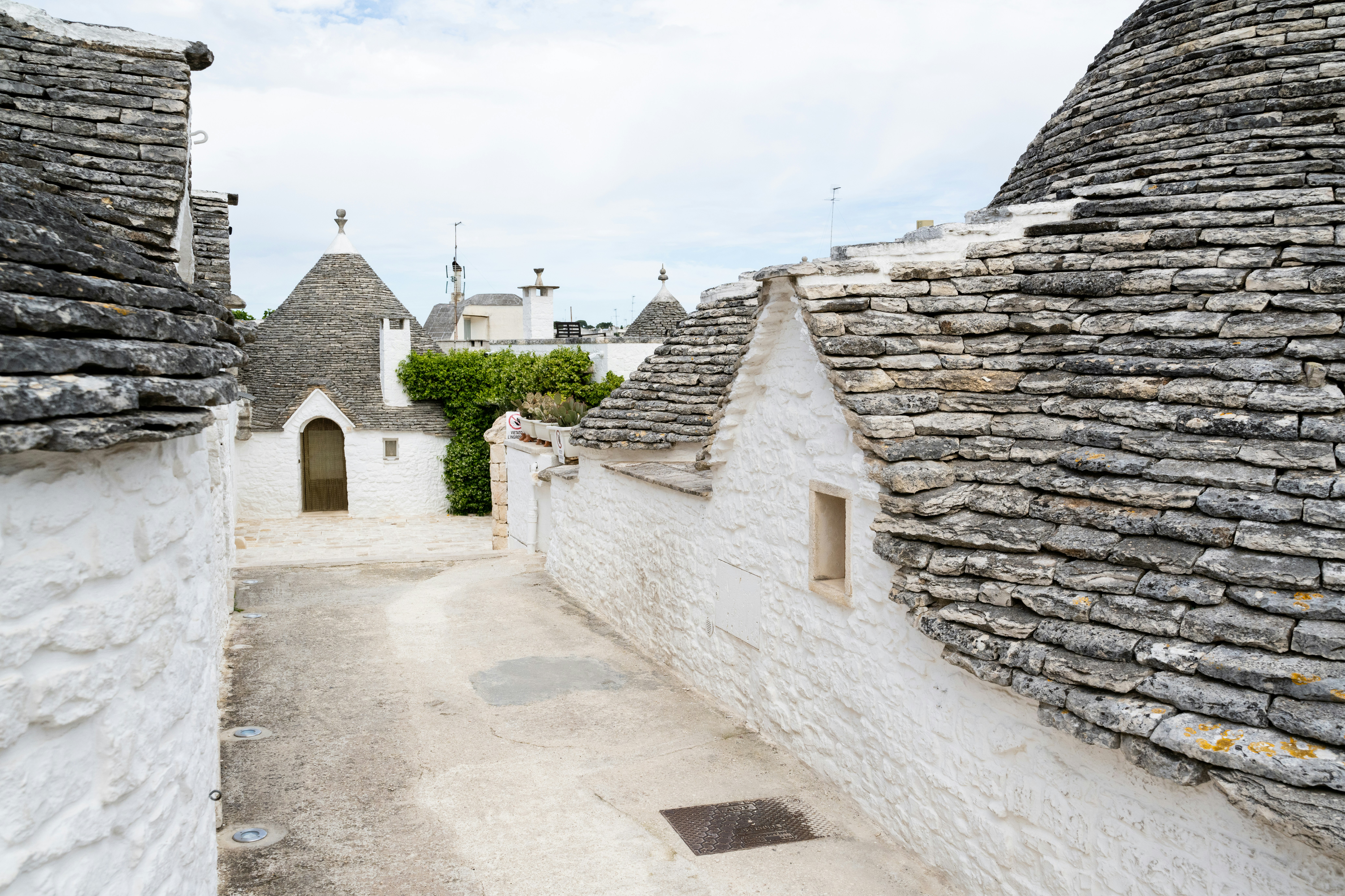 Narrow alleyway between white trulli houses in italy.