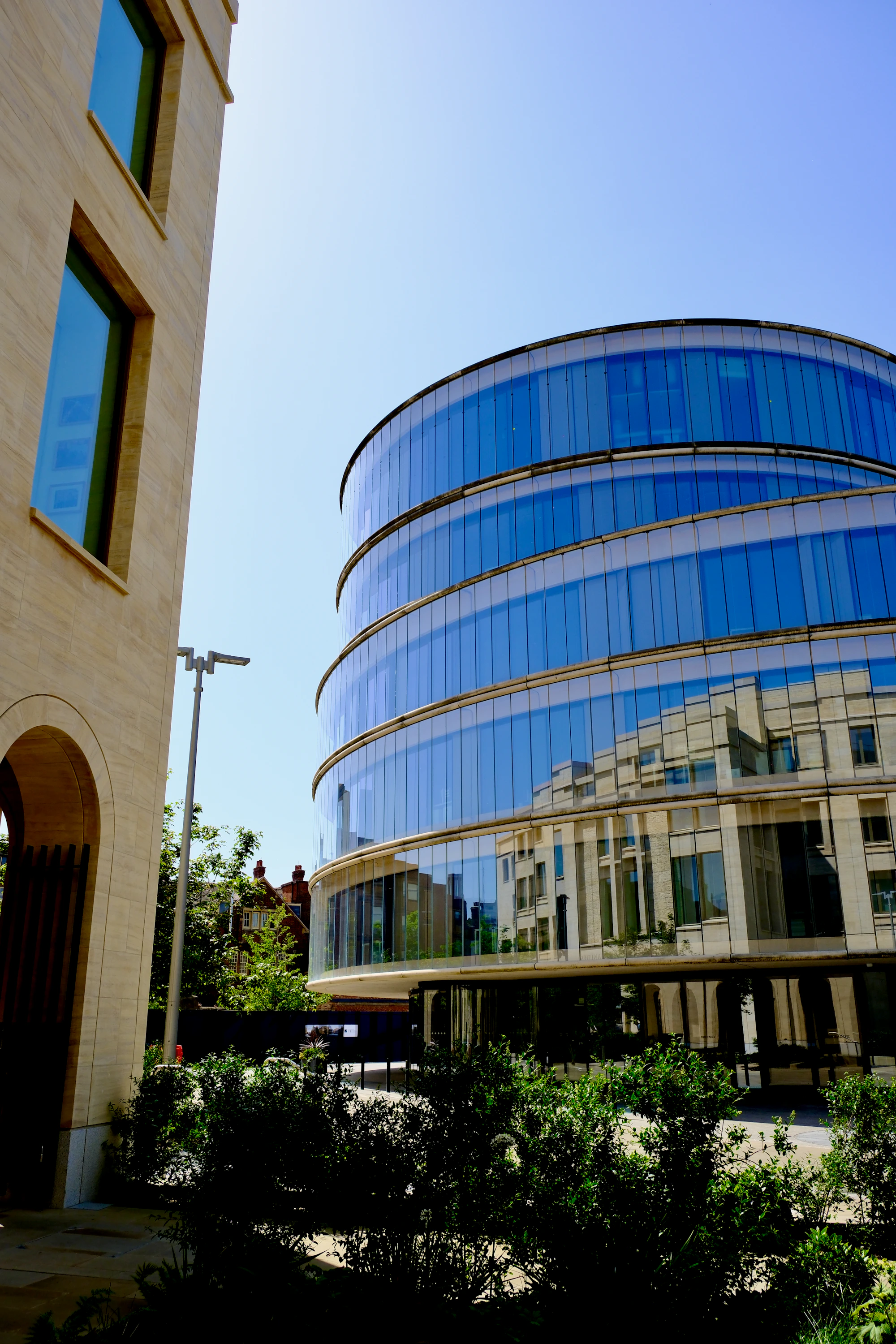 Curved modern glass building beside a traditional stone building