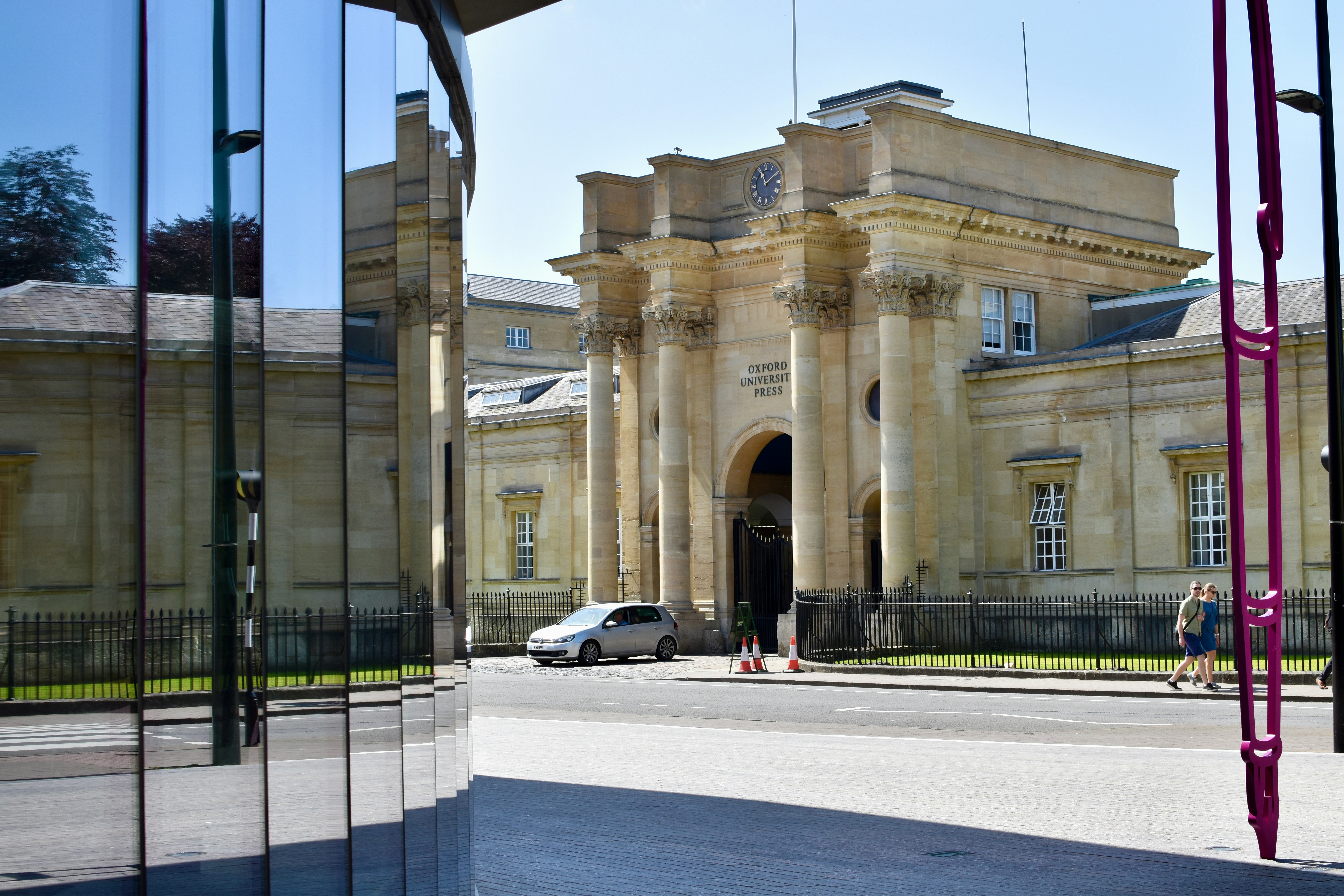 Classical building facade, street with car, and modern glass reflections.