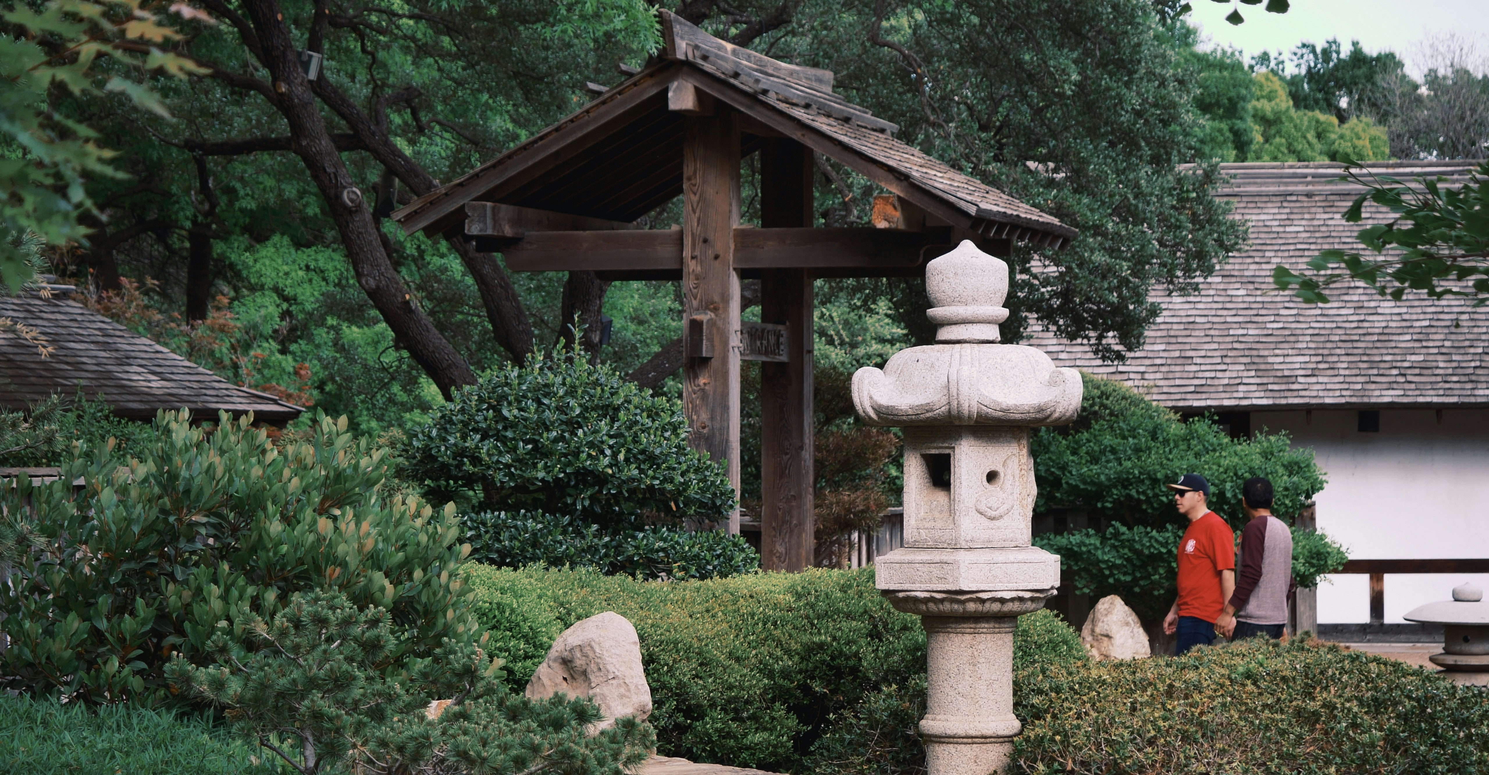 Stone lantern and wooden pavilion in a tranquil garden.