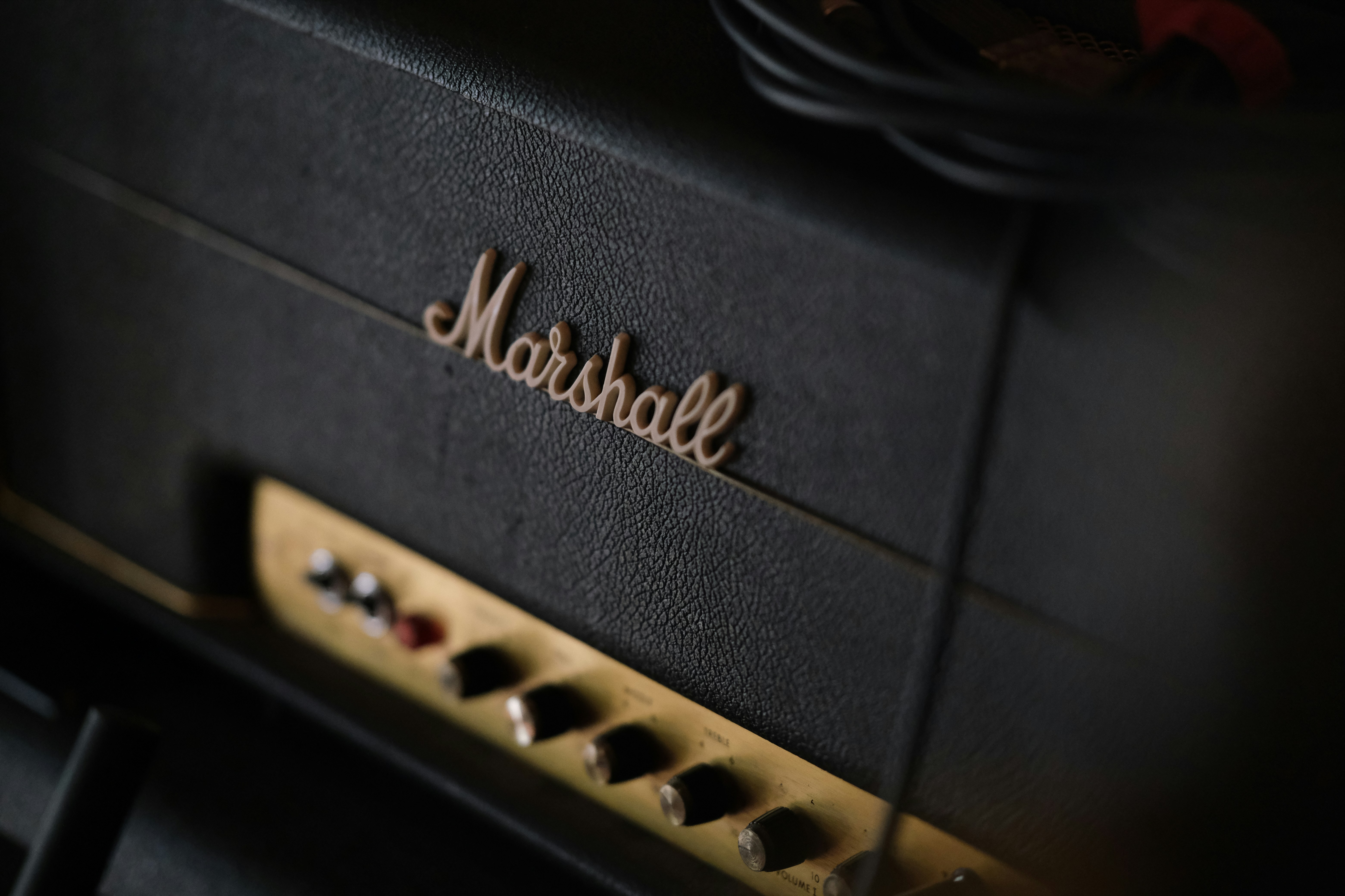 A black marshall guitar amplifier with gold control knobs.