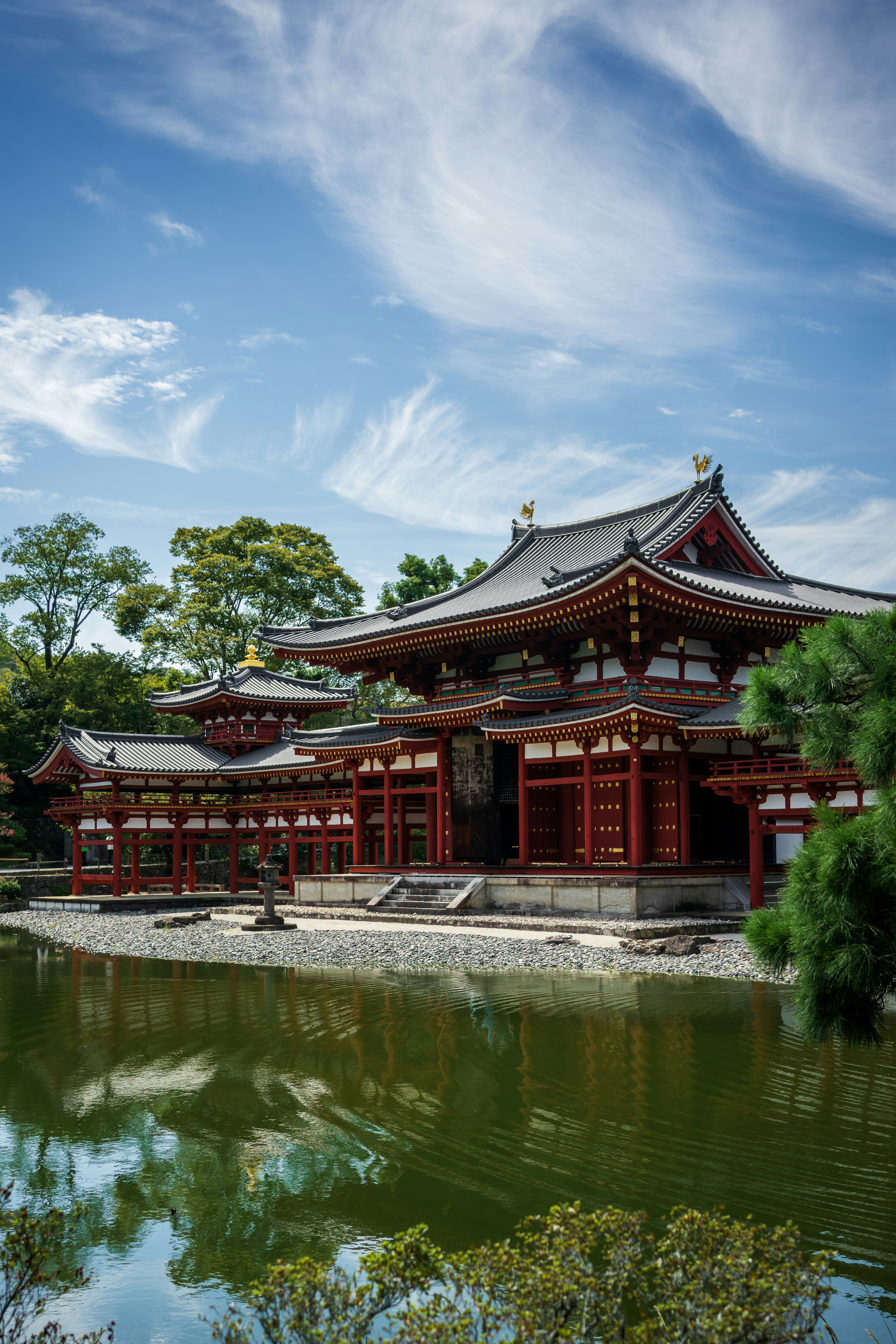 Traditional japanese temple with red accents reflected in water.