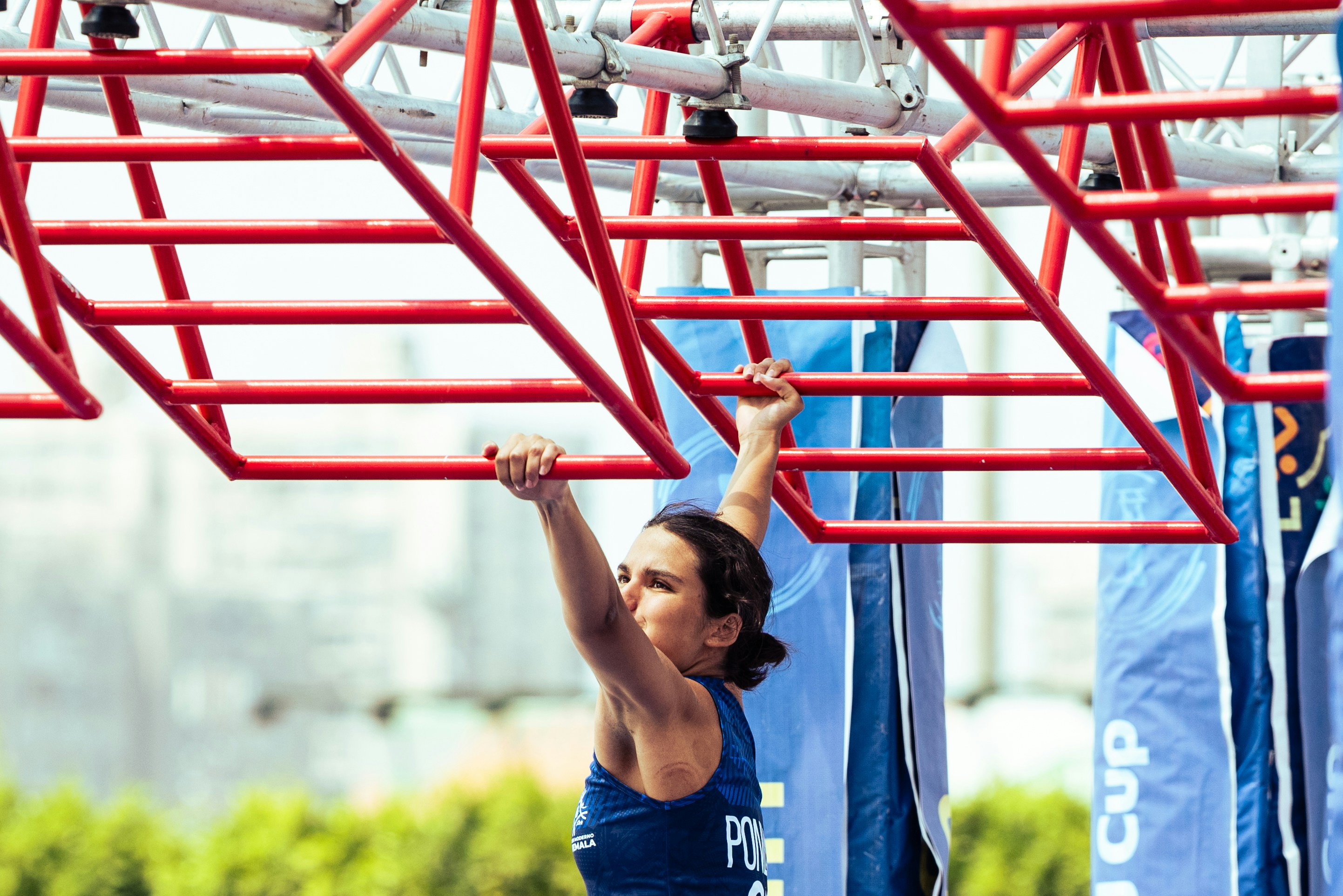 A woman navigates a red monkey bar obstacle course.