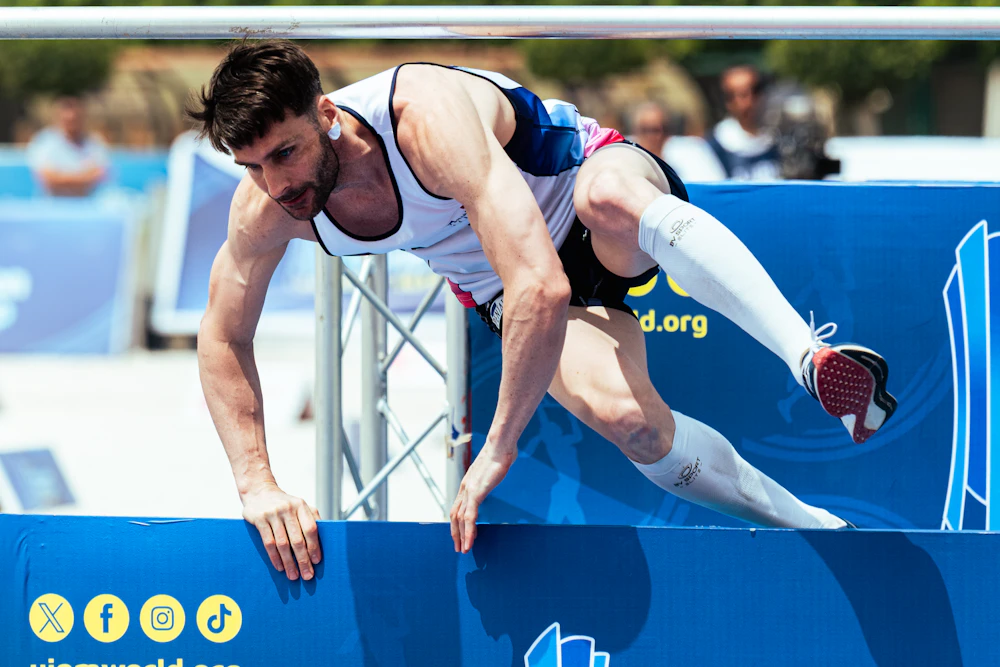 Mid-run, an athlete clears a barrier under competition pressure
