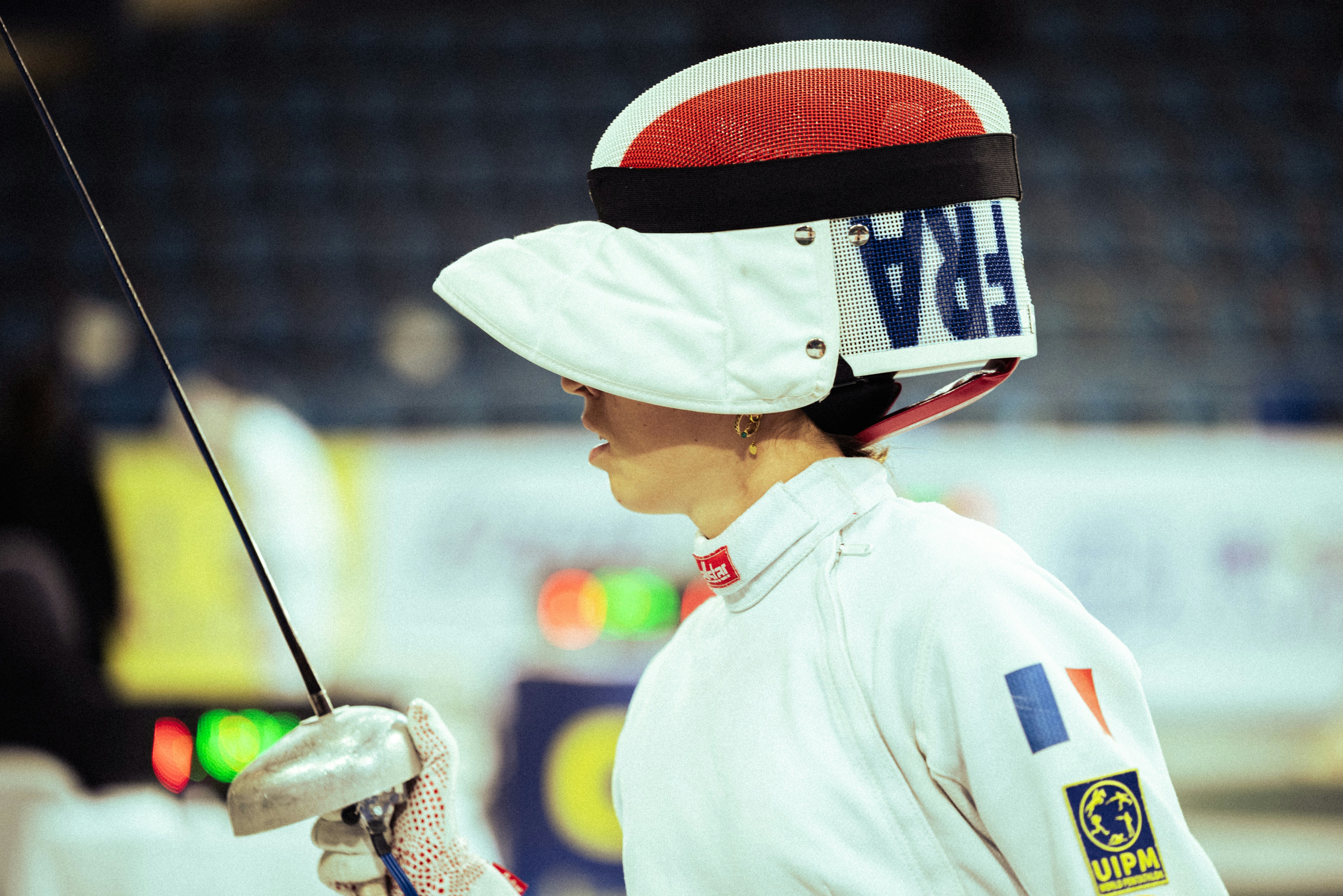 Esgrimista francês com uniforme branco e capacete com florete.