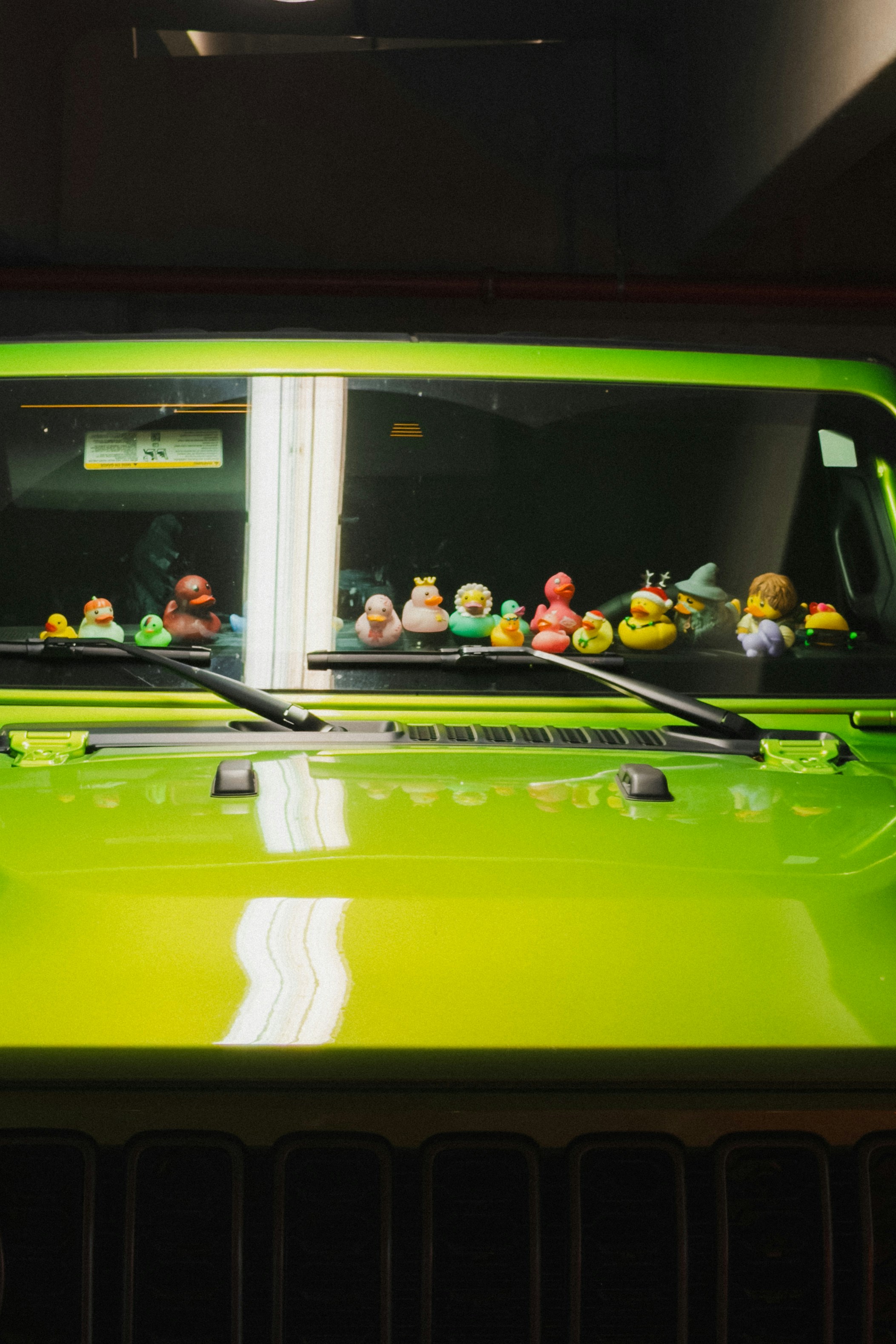 Jeep hijau cerah menampilkan banyak bebek karet di dasbornya.