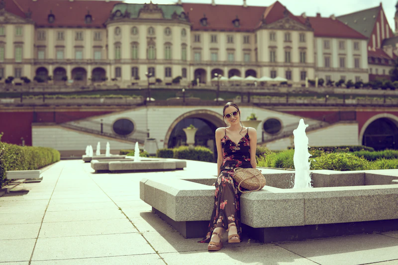woman in floral dress by fountains near a palace