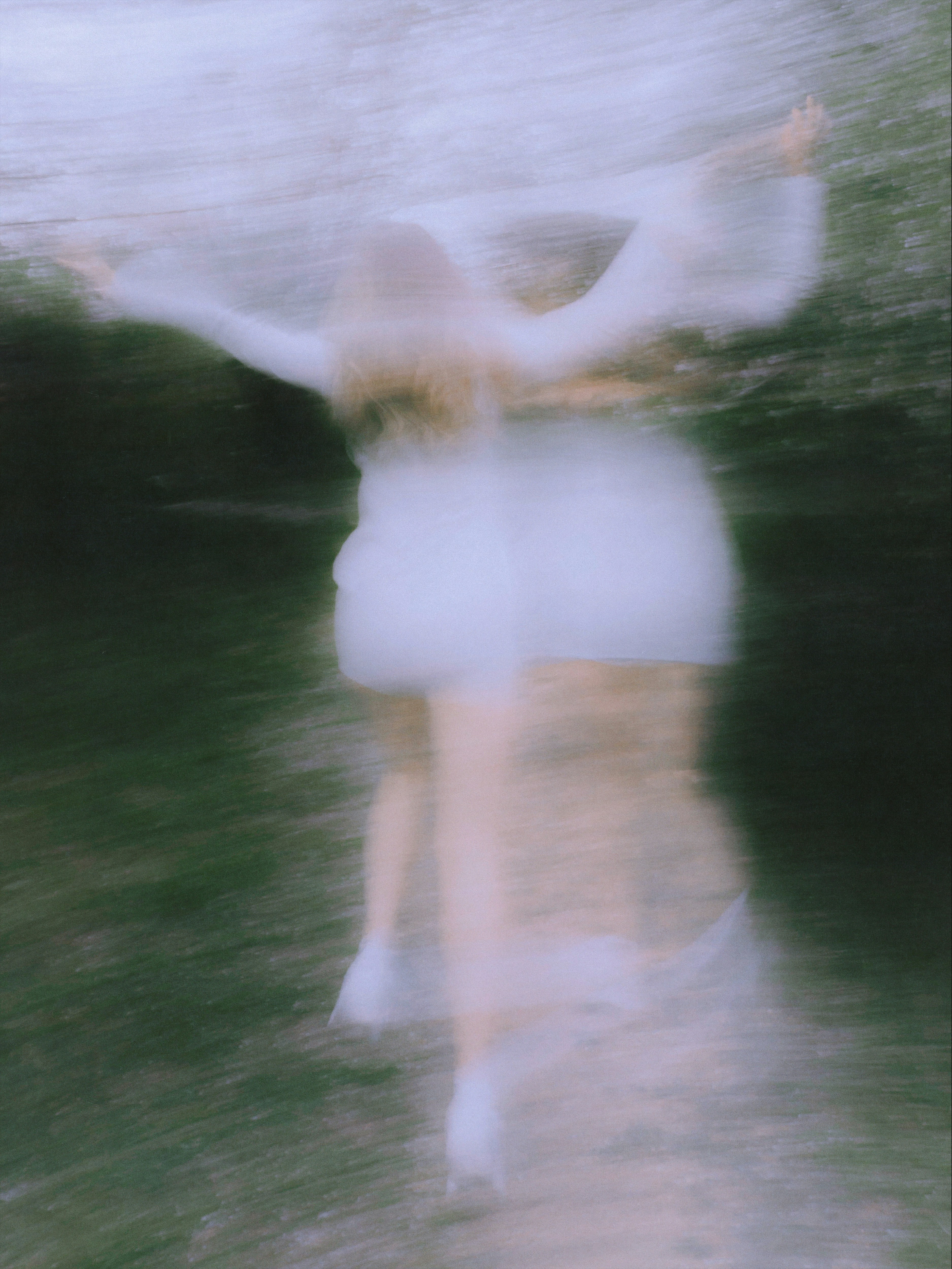 Blurry figure with outstretched arms in motion outdoors