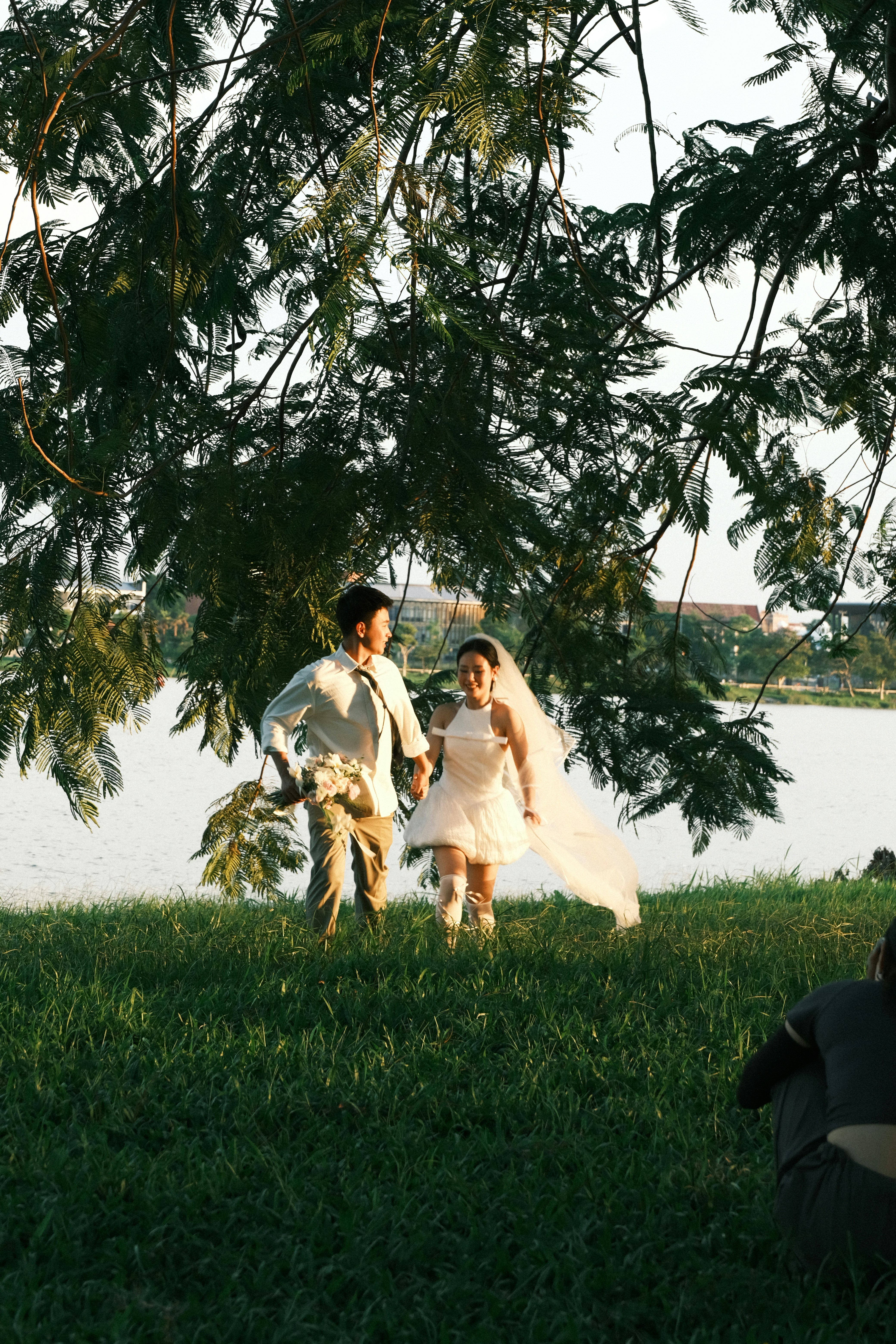 Niño y niña jóvenes con traje de boda junto a un lago.