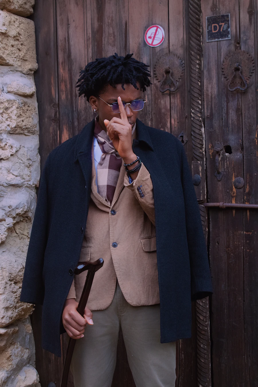 Man in a dark coat holding a straight wooden cane