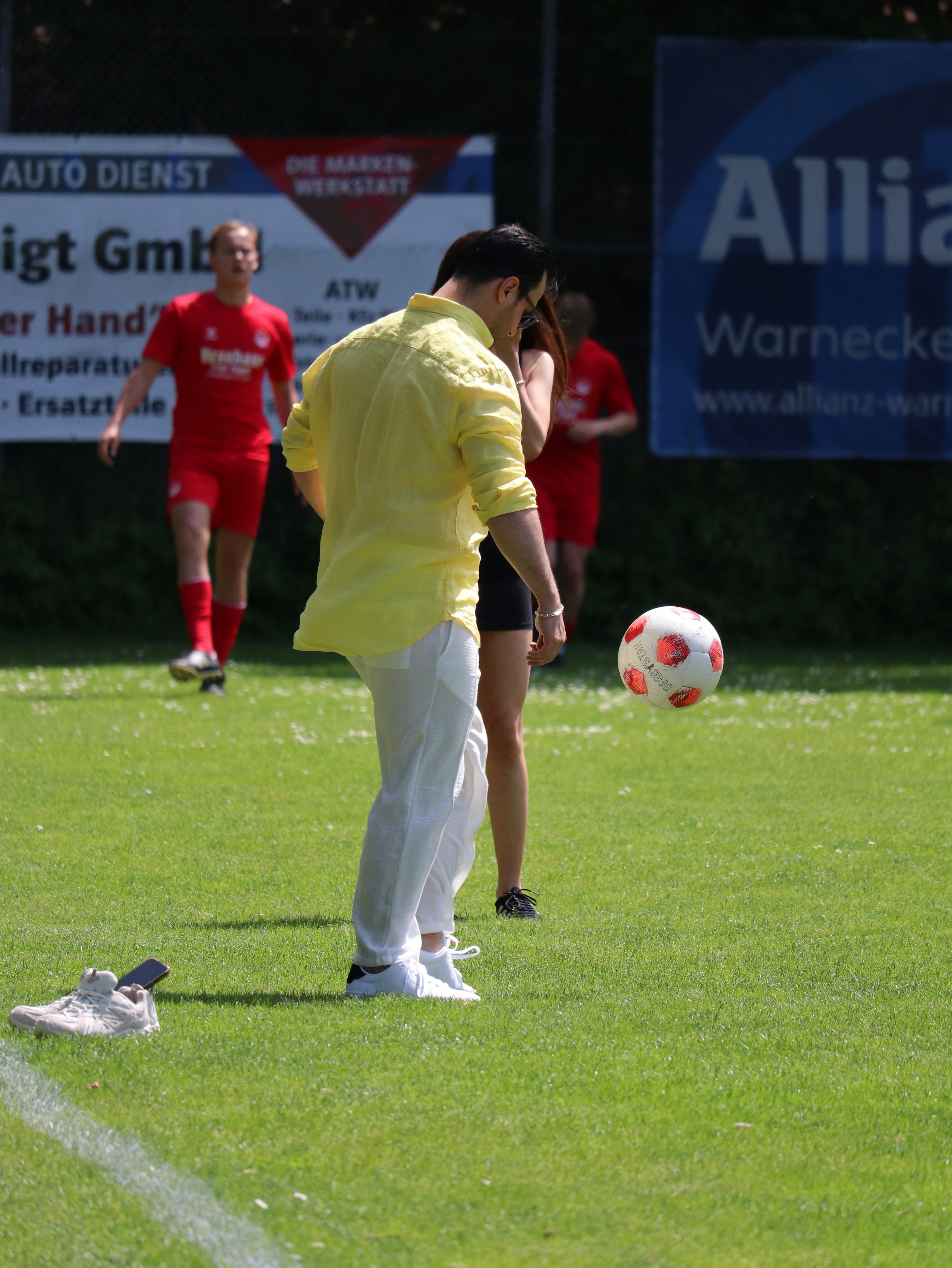 Pria berbaju kuning menendang bola sepak di lapangan rumput.