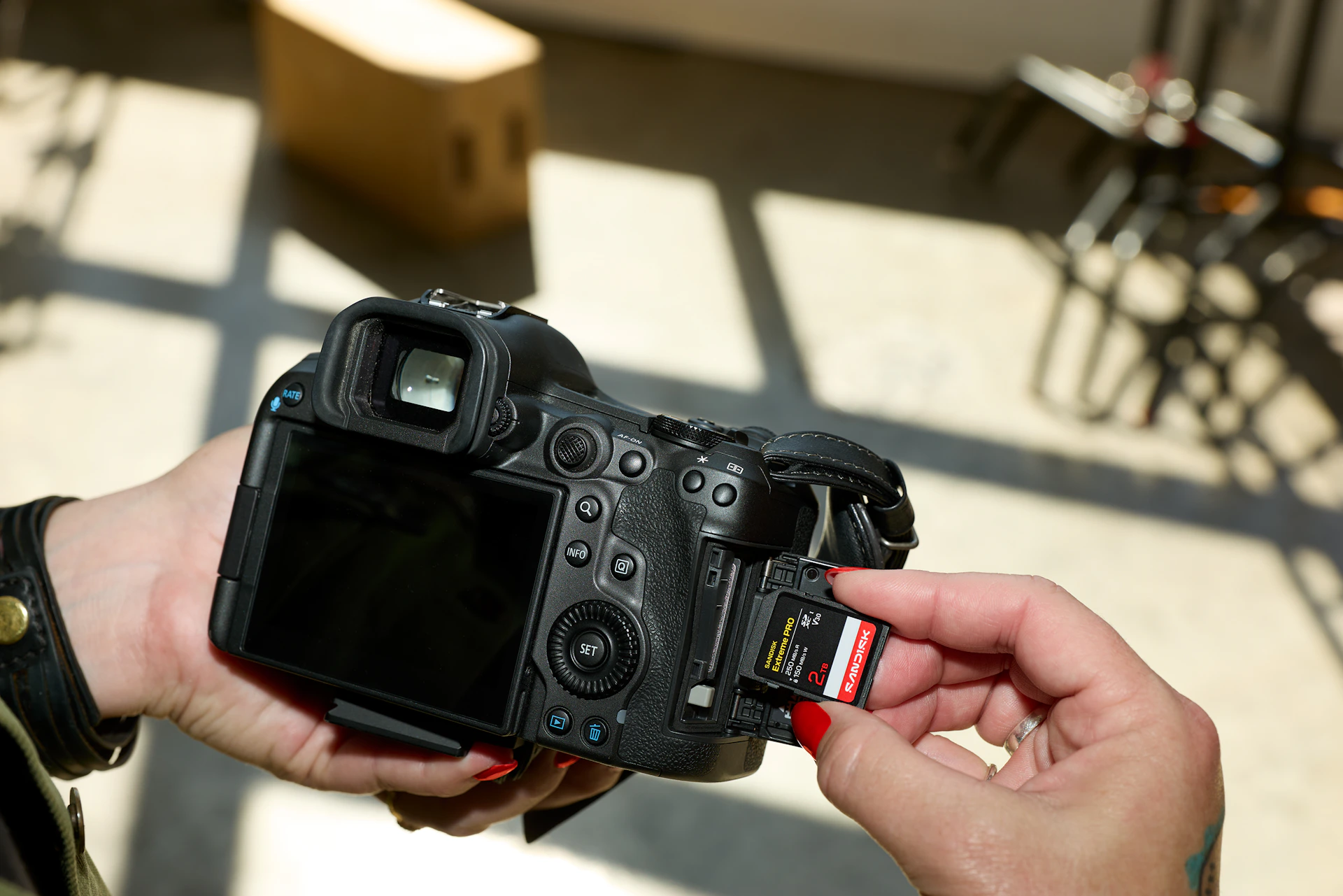 Hands inserting a memory card into a black dslr camera.
