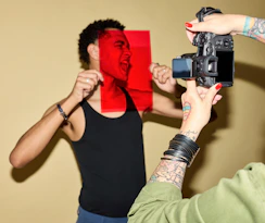 Man's face through red filter, being photographed by camera.