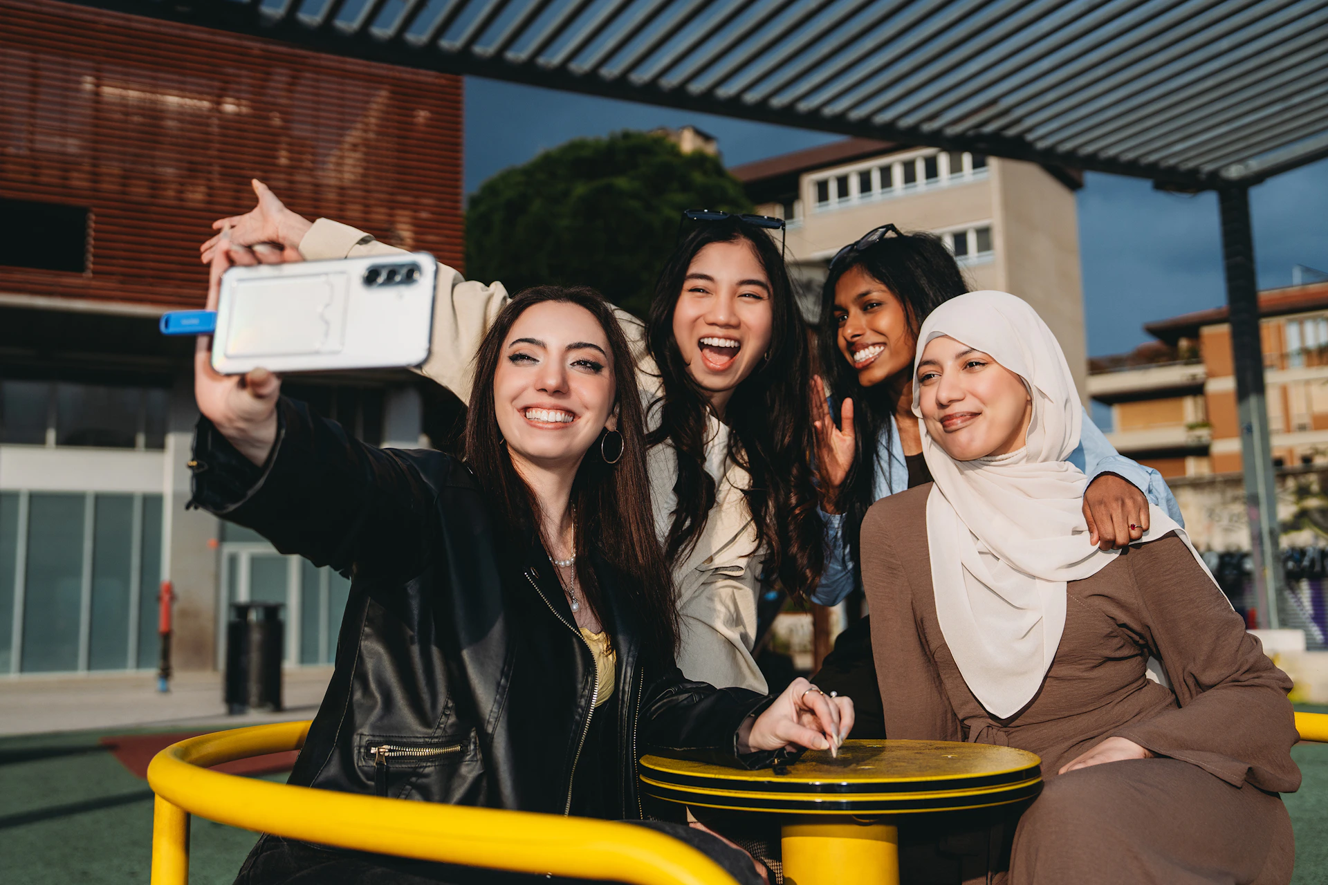 Four happy young women taking a selfie outdoors.