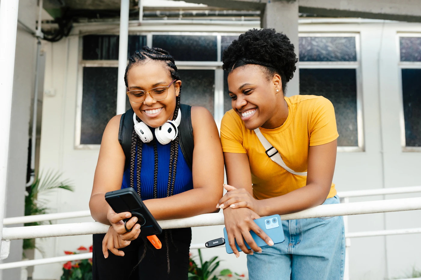 Deux amies rient en regardant un téléphone, l’une montre quelque chose à l’autre
