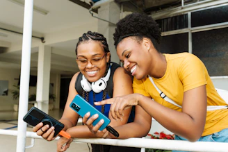 Two smiling women looking at a smartphone together.