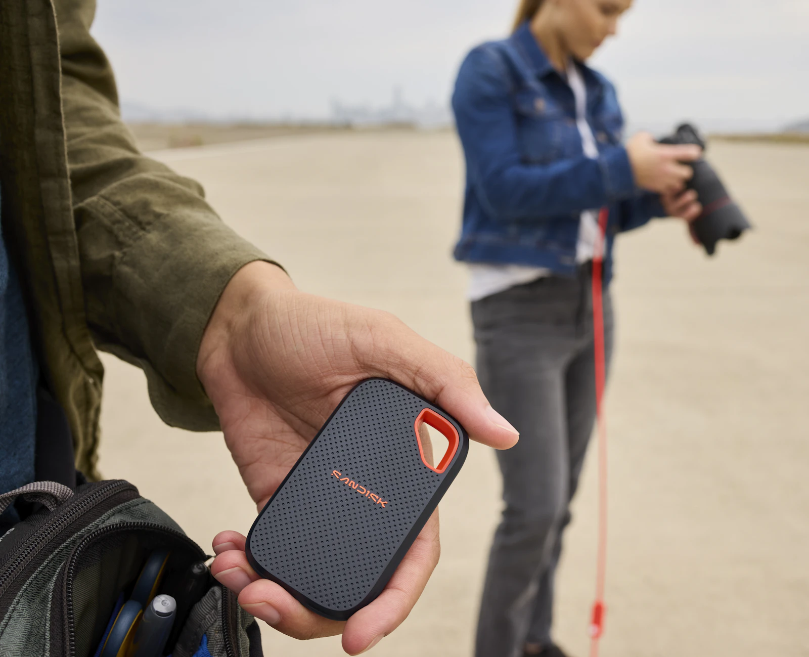 A photographer holding a portable SSD on location with camera equipment