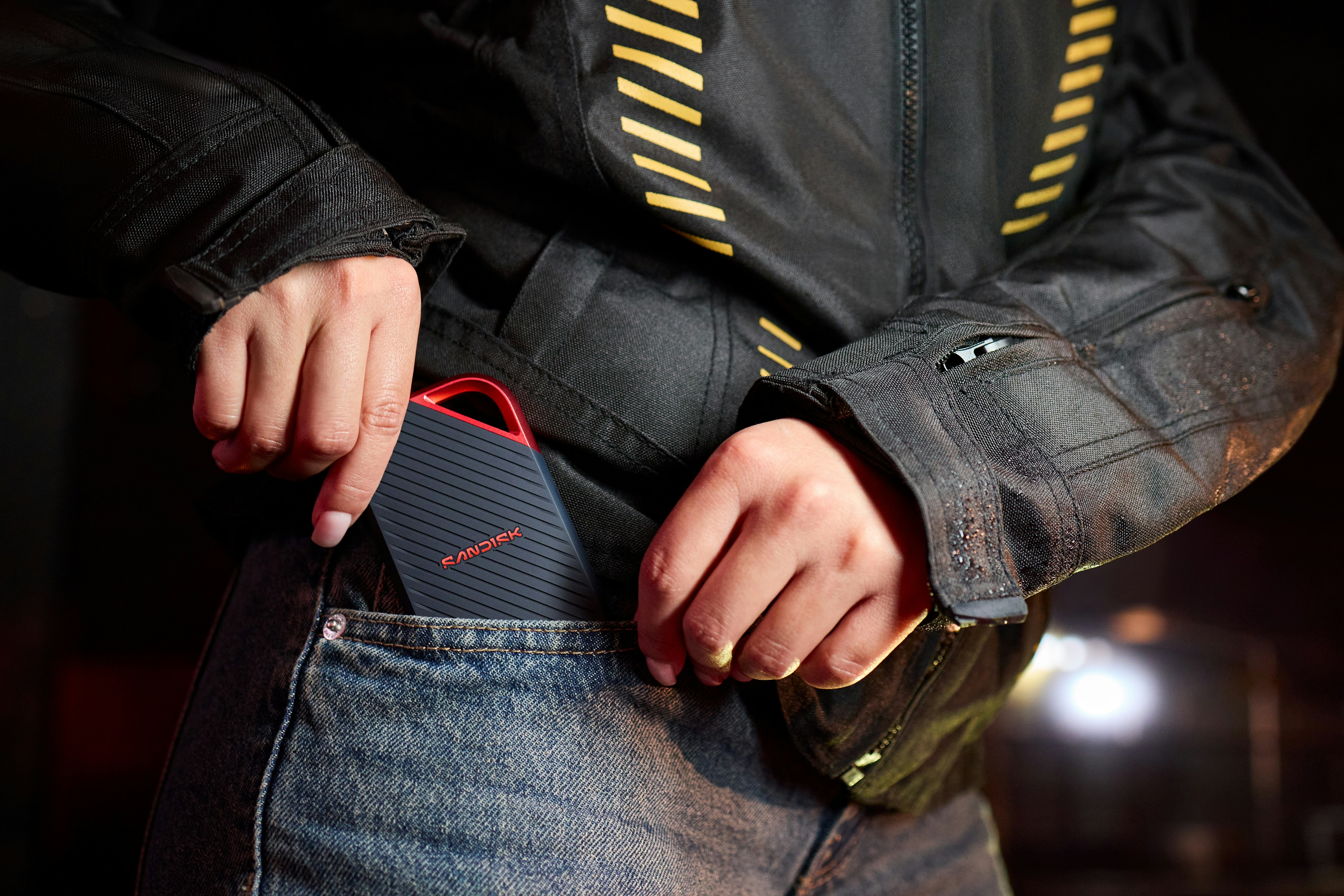 Seseorang memasukkan speaker portabel ke dalam saku jeans.