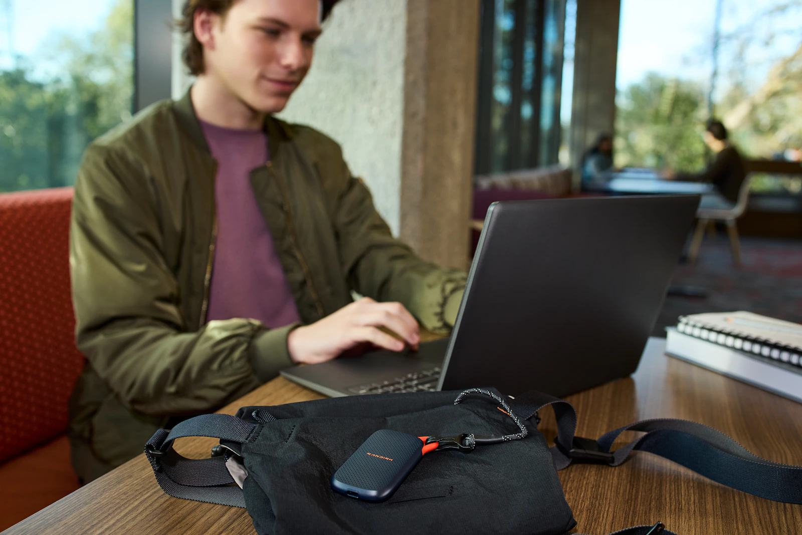 Person using a laptop with a portable storage device on the table