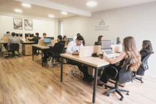 Modern open-plan office with employees working at individual workstations.