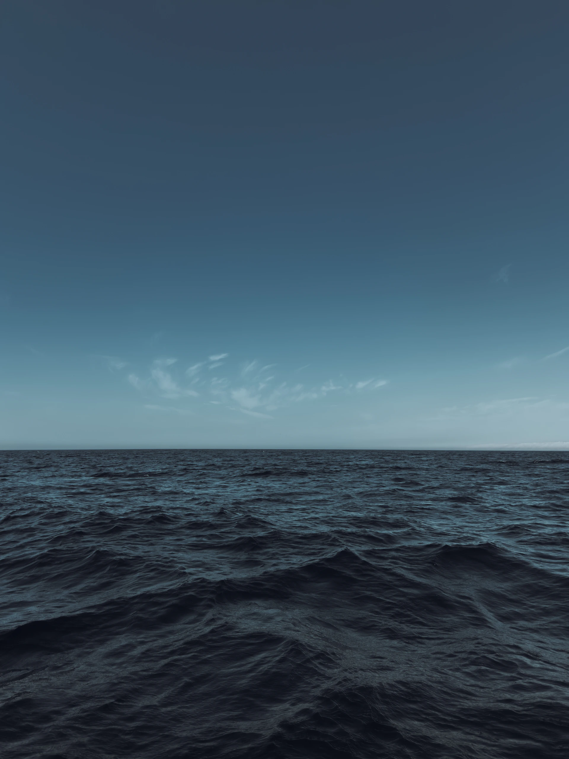 Dark blue ocean waves under a clear blue sky.