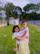 A girl carrying another girl in a green outdoor area.