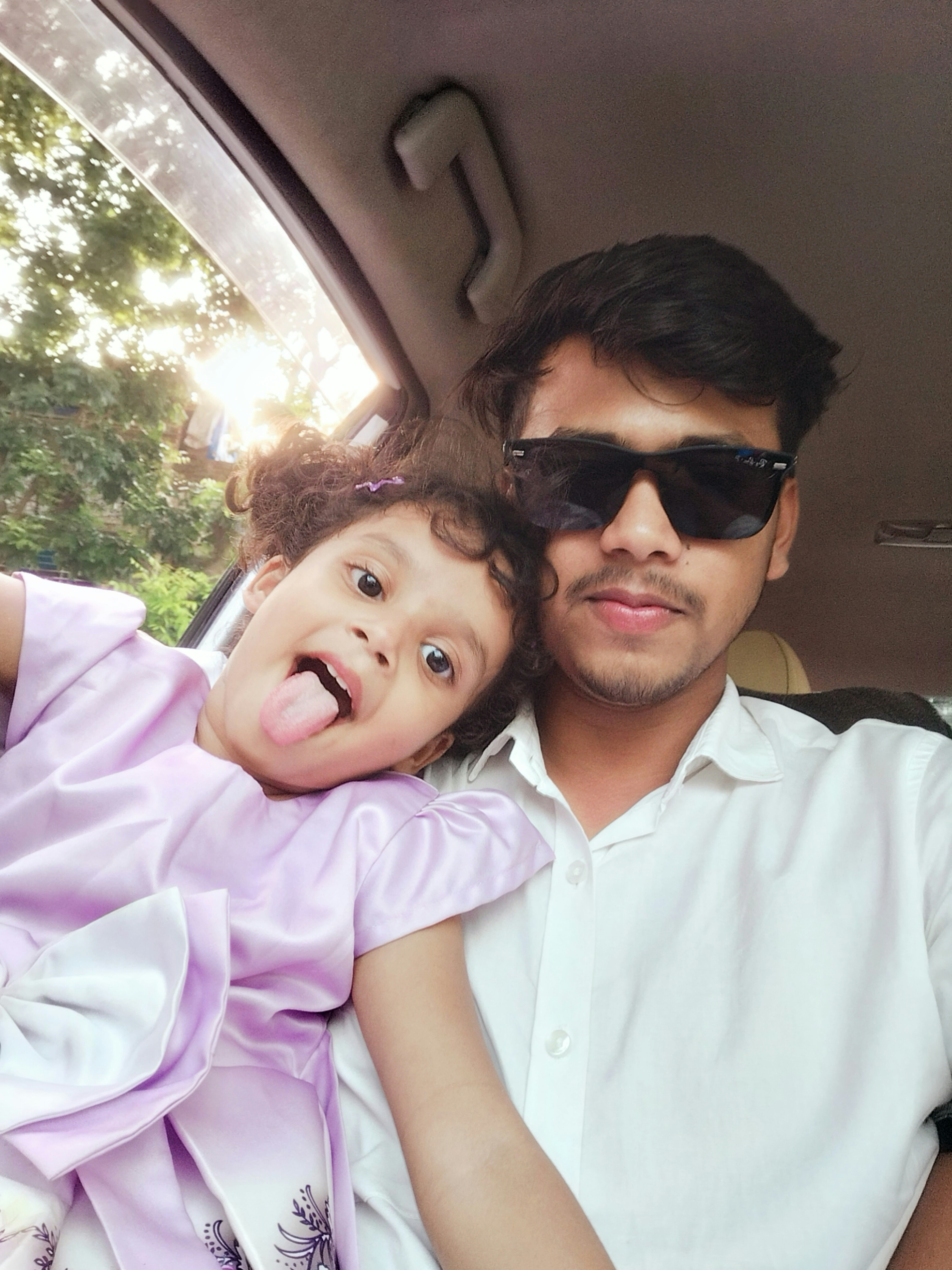 Man and girl pose playfully in a car